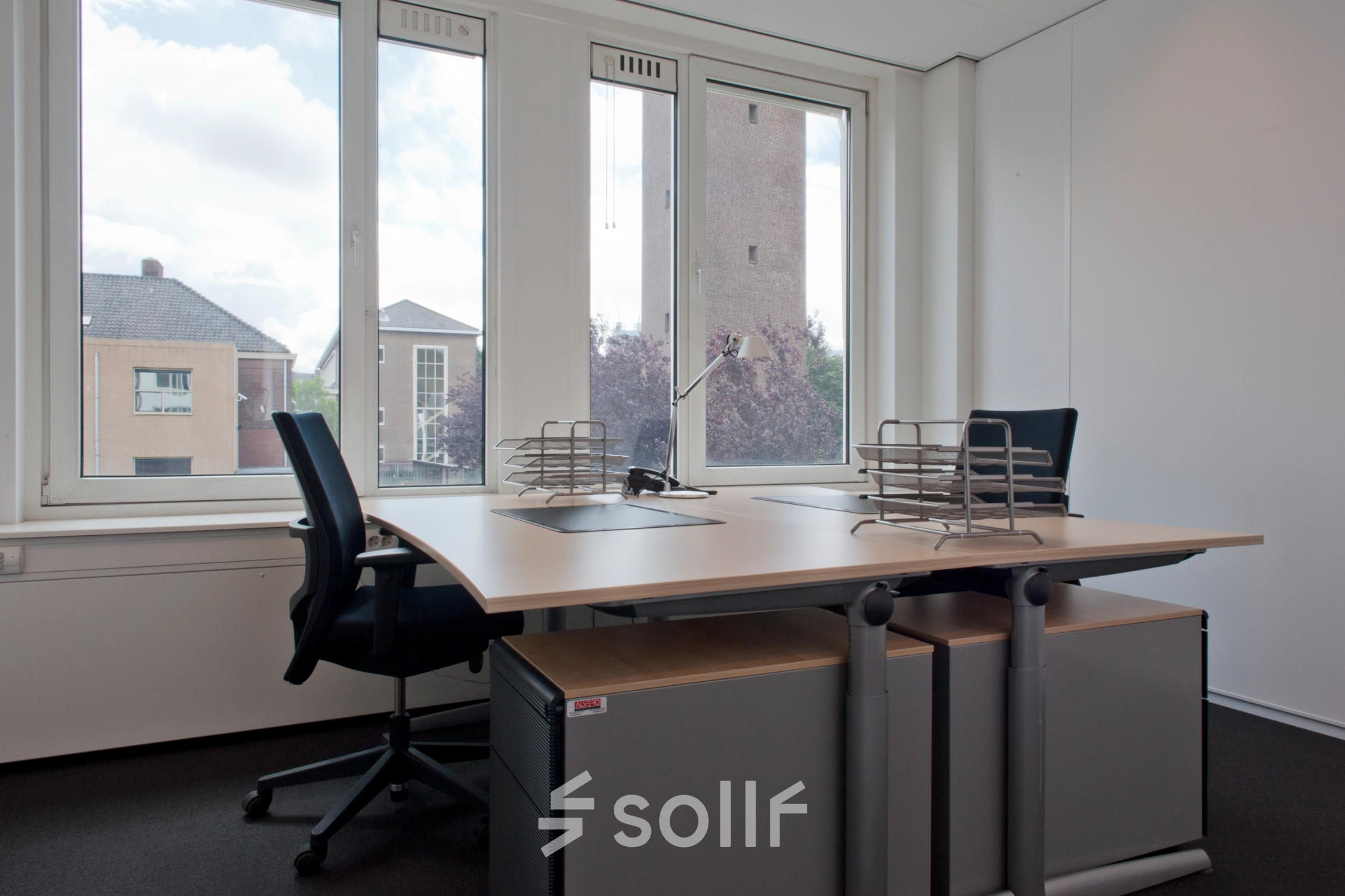 Kantoorruimte huren op Bezuidenhoutseweg 161, Den Haag Haagse Hout. De lichte ruimte heeft een groot raam, twee bureaus met stoelen en een uitzicht op omliggende gebouwen.