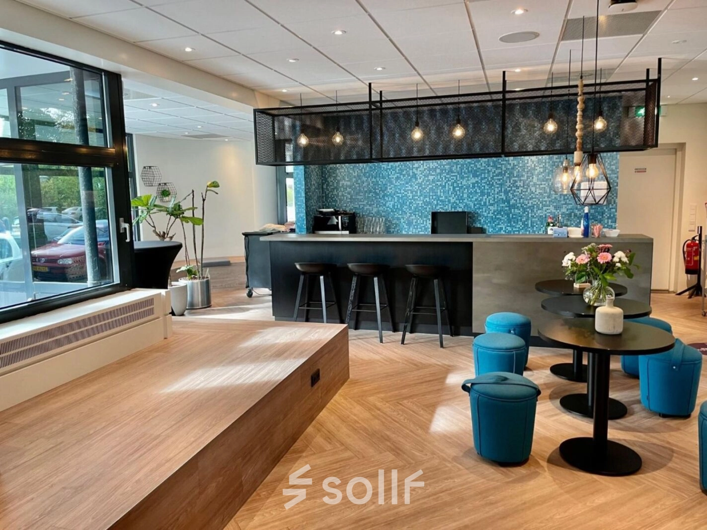 Moderne lounge in kantoorpand op Johan de Wittlaan 3-7, Den Haag Statenkwartier, met zithoek, barkrukken en decoratieve verlichting. Ideaal voor kantoorruimte huren.