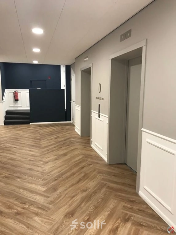 Een moderne, goed verlichte kantoorruimte met houten vloer, twee liften en een trap aan de Johan de Wittlaan 3-7, Den Haag Statenkwartier, ideaal voor kantoren te huur.