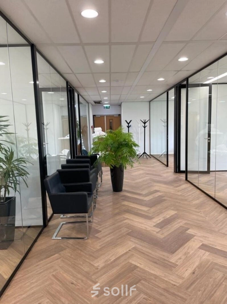 Moderne kantoorruimte met glazen wanden, houten vloer en enkele zwarte stoelen aan Johan de Wittlaan 3-7 in Den Haag Statenkwartier.