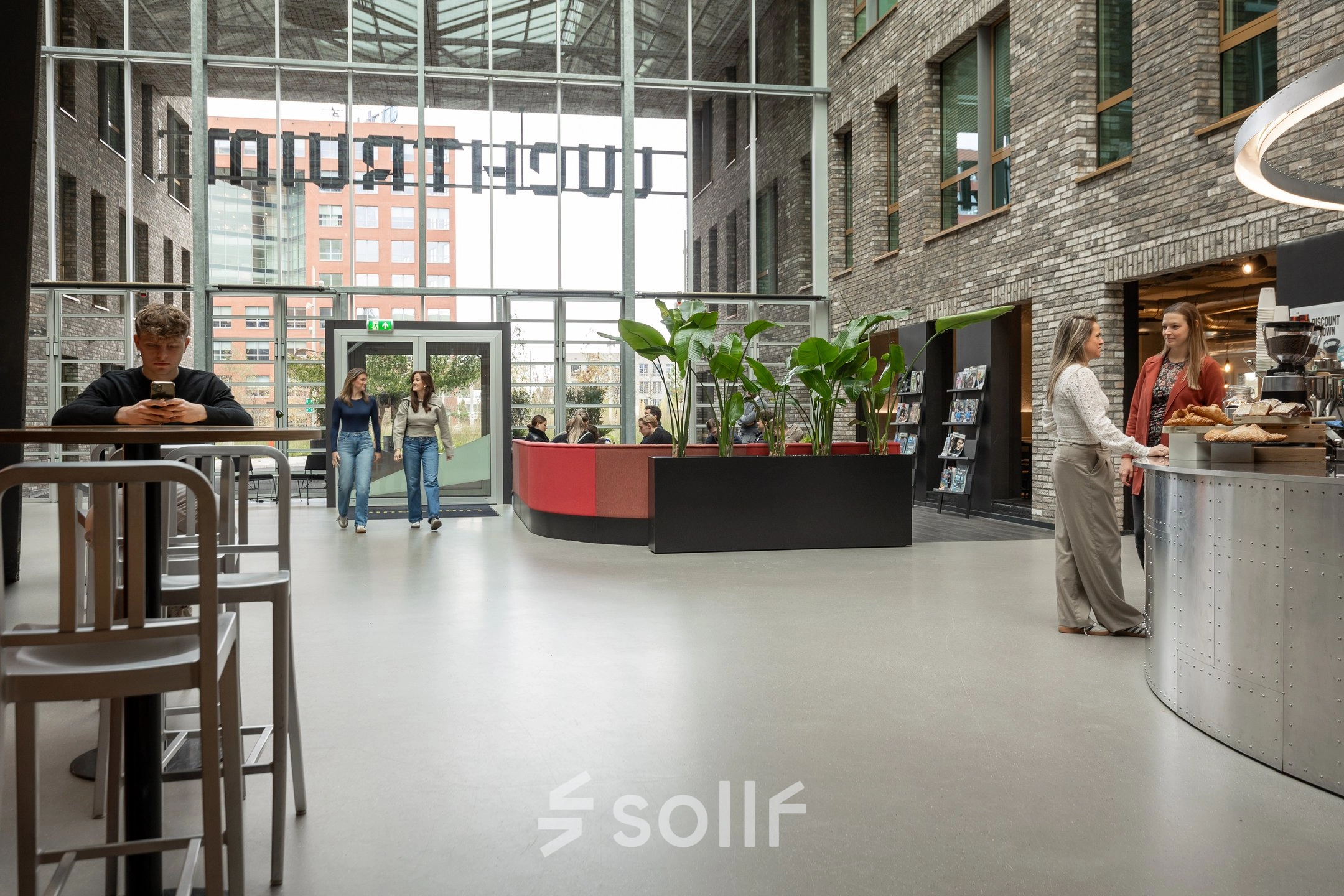 Moderne en lichte kantoorruimte op Flight Forum 120-159, Eindhoven Airport. Mensen wisselen ideeën uit bij het koffiepunt. Perfecte plek voor je volgende kantoor om te huren.