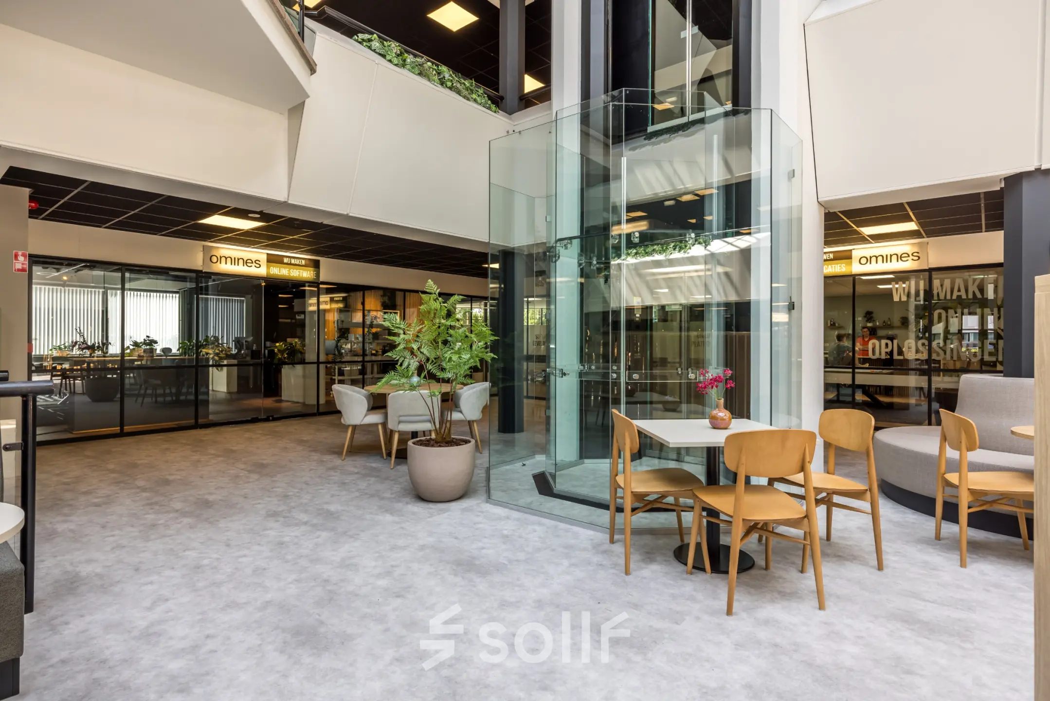 Moderne kantoorruimte huren in Eindhoven Airport met glazen lift en zitgedeelte rondom, ideaal voor flexwerken.