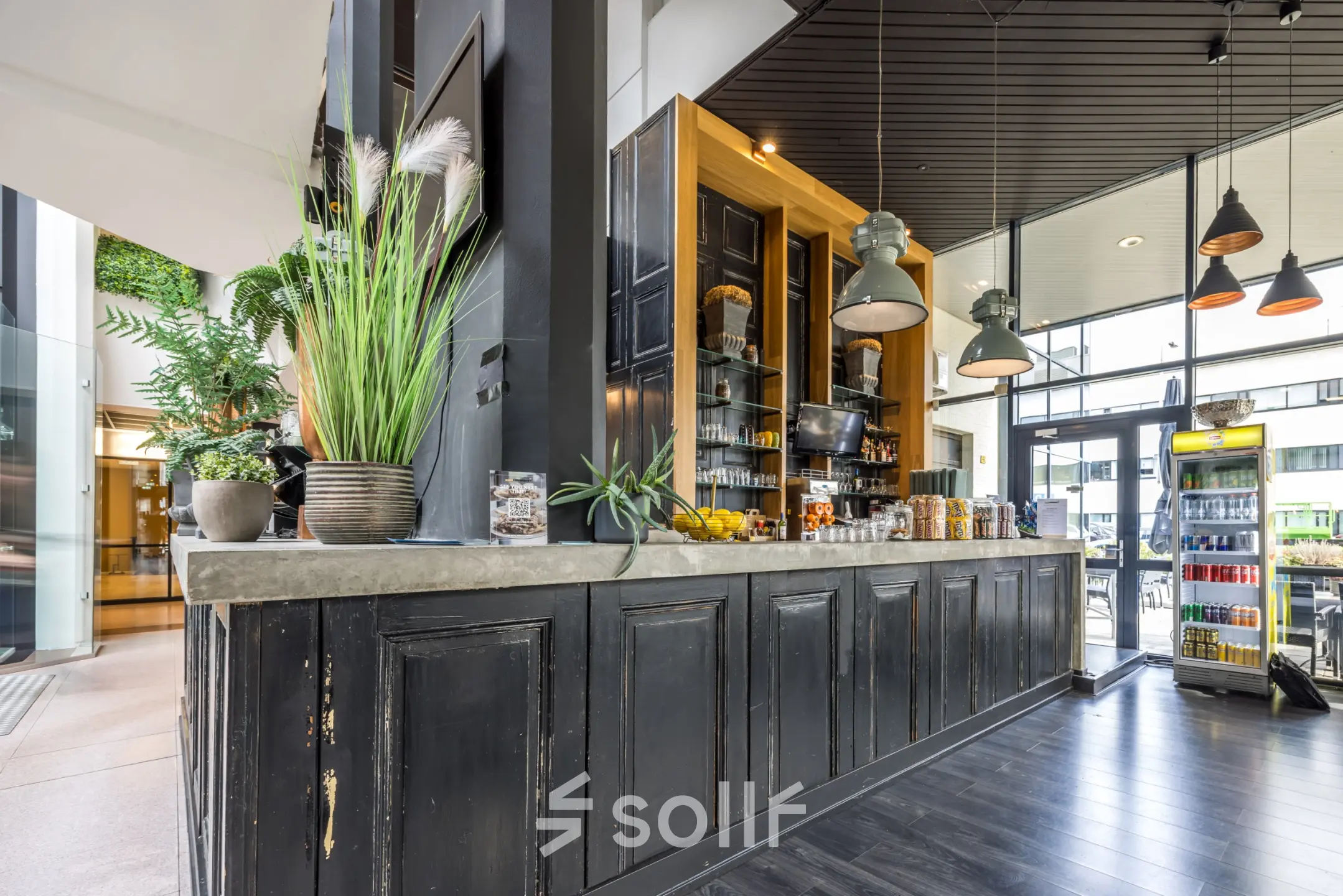 Sfeervolle kantoorruimte huren op Luchthavenweg 81, Eindhoven Airport, met een gezellige ontvangstruimte en stijlvolle bar. Perfecte locatie voor zakelijke ontmoetingen en netwerkkansen in een moderne kantoorpandomgeving.
