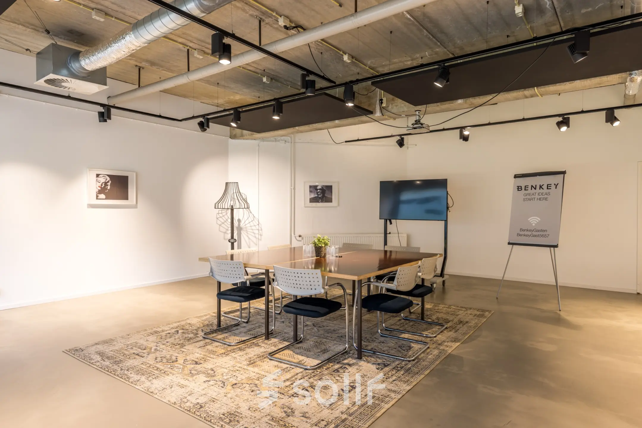 Stijlvol ingerichte kantoorruimte op Luchthavenweg 81, Eindhoven Airport, met een vergadertafel, stoelen en kunstwerken aan de muur. Perfect om te huren voor diverse zakelijke activiteiten.