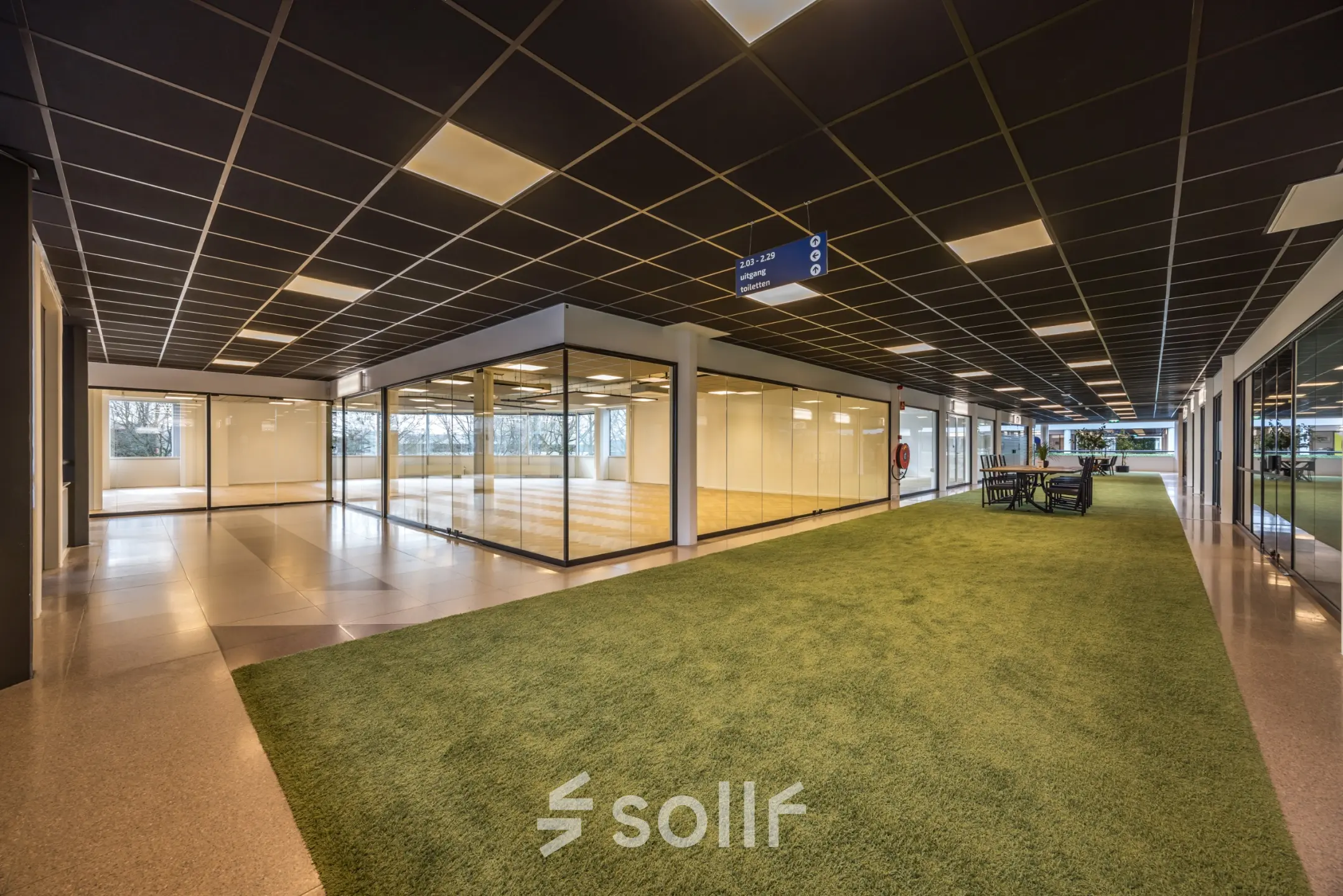Moderne kantoorruimte te huur op Luchthavenweg 81, Eindhoven Airport, met grote glazen wanden en groene accenten binnen het kantoorpand.