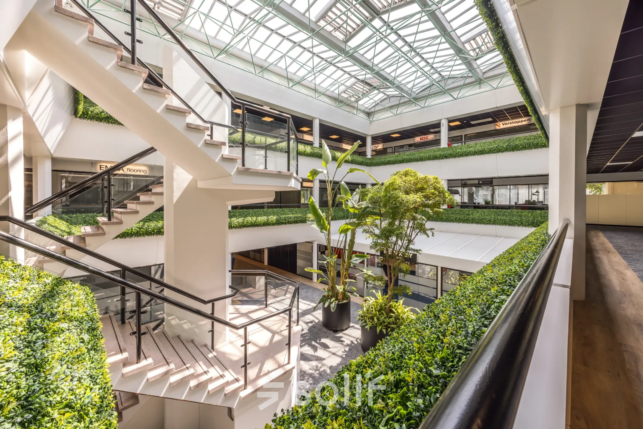 Ruim atrium van het kantoorpand op Luchthavenweg 81, Eindhoven Airport, met veel groen en open trappenhuis. Ideaal voor kantoorruimte huren met een moderne uitstraling.