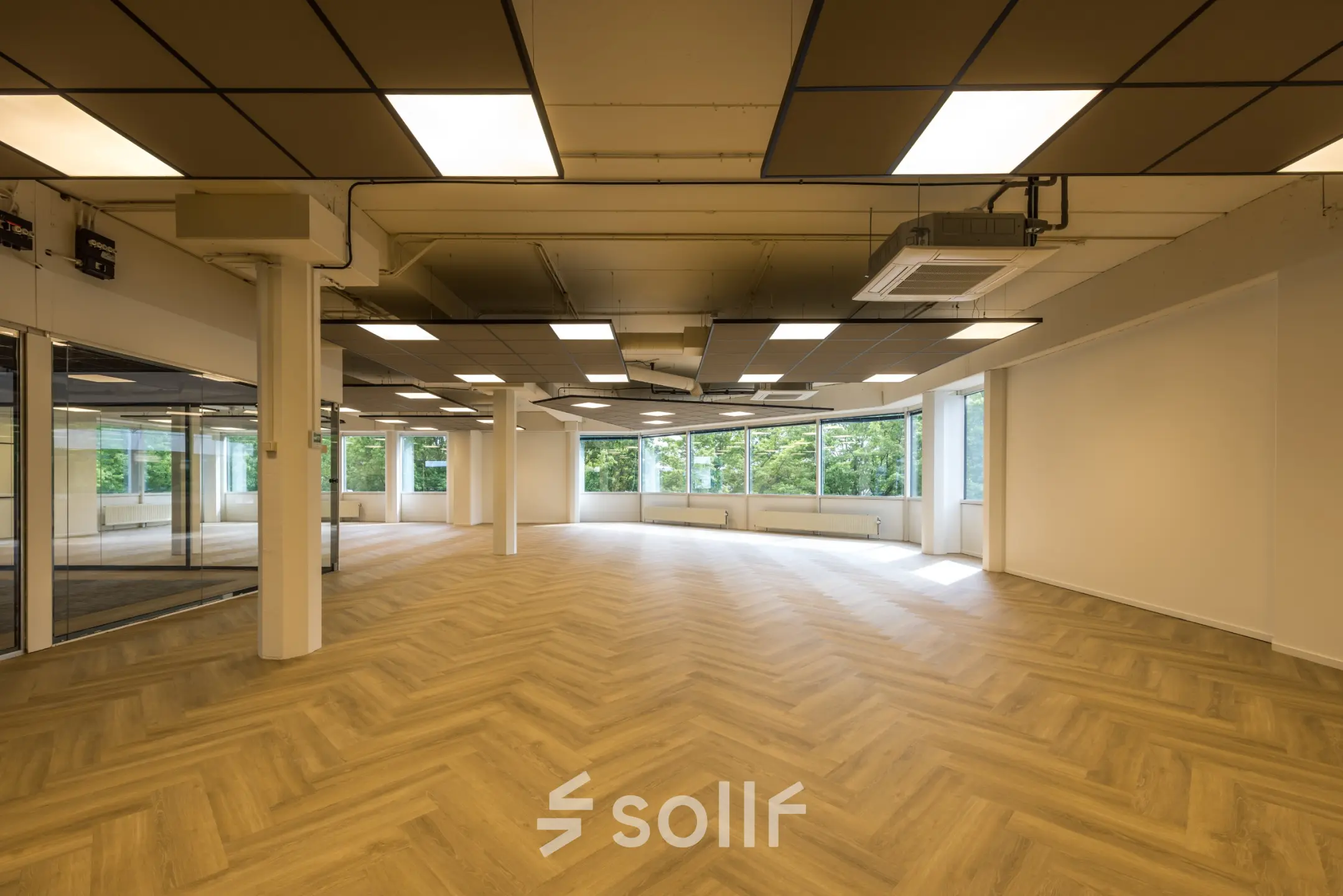 Ruime en lichte kantoorruimte op Eindhoven Airport met een modern plafond ontwerp en grote ramen voor natuurlijk licht.