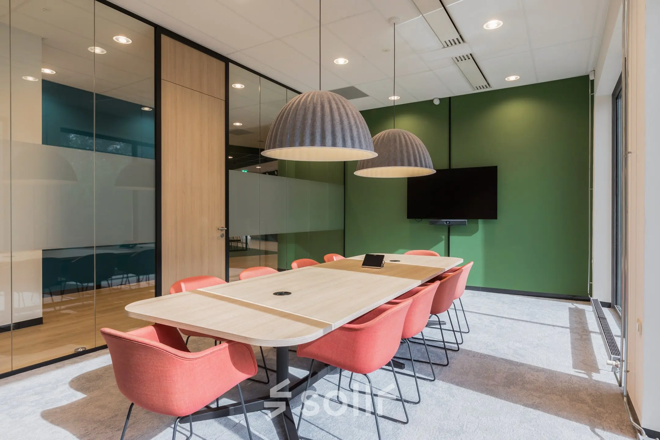 Vergaderruimte in kantoorpand met moderne verlichting, houten tafel en rode stoelen, gelegen op Professor Dr Dorgelolaan 14, Eindhoven Centrum. Ideale plek voor kantoorruimte huren.