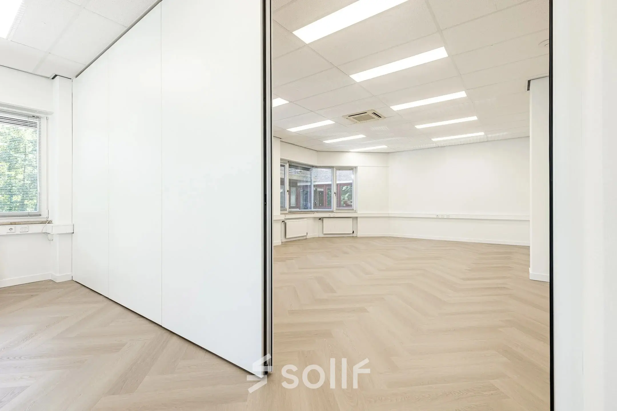 Heldere, open kantoorruimte in Eindhoven De Hurk met grote ramen en houten vloerpatroon, ideaal voor kantoorruimte huren. Flexibele wanden bieden mogelijkheid tot verschillende indelingen.