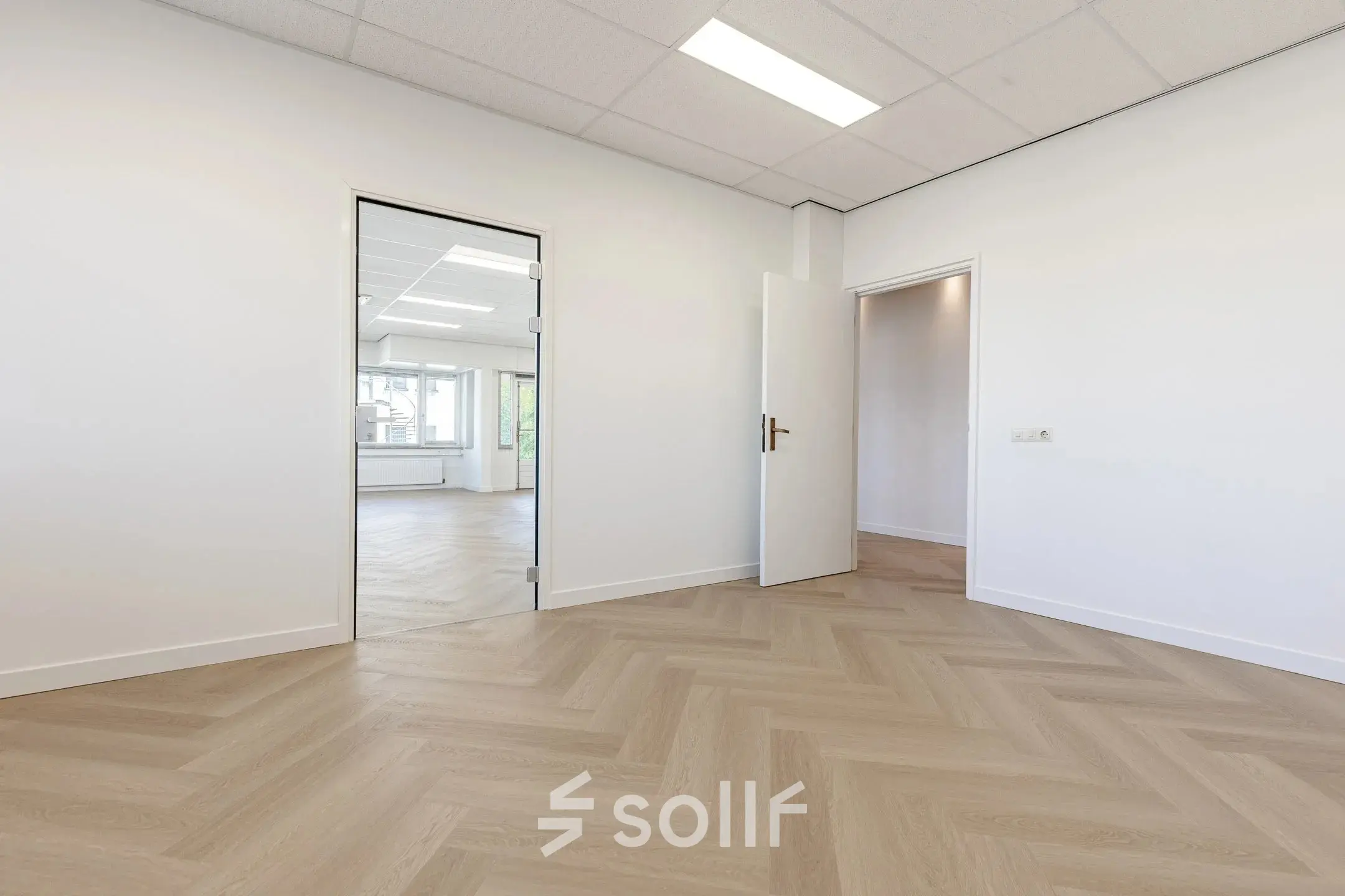 Lege kantoorruimte in Eindhoven De Hurk, te huur met houten vloer en brede openingen naar andere kamers.