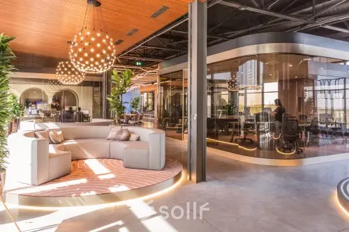 Moderne kantoorruimte huren in kantoorpand op Achtseweg Zuid 159R, Eindhoven Strijp-S, met stijlvolle meubels en grote ramen. Personen werken in een vergaderruimte en open werkplekken.