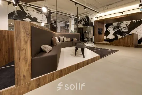 Moderne kantoorruimte met stijlvolle houten en bruine details, comfortabele zitplaatsen en kunstzinnige decoraties op de muren. Een ideale plek voor informele vergaderingen of ontspanning in Eindhoven Strijp-S.