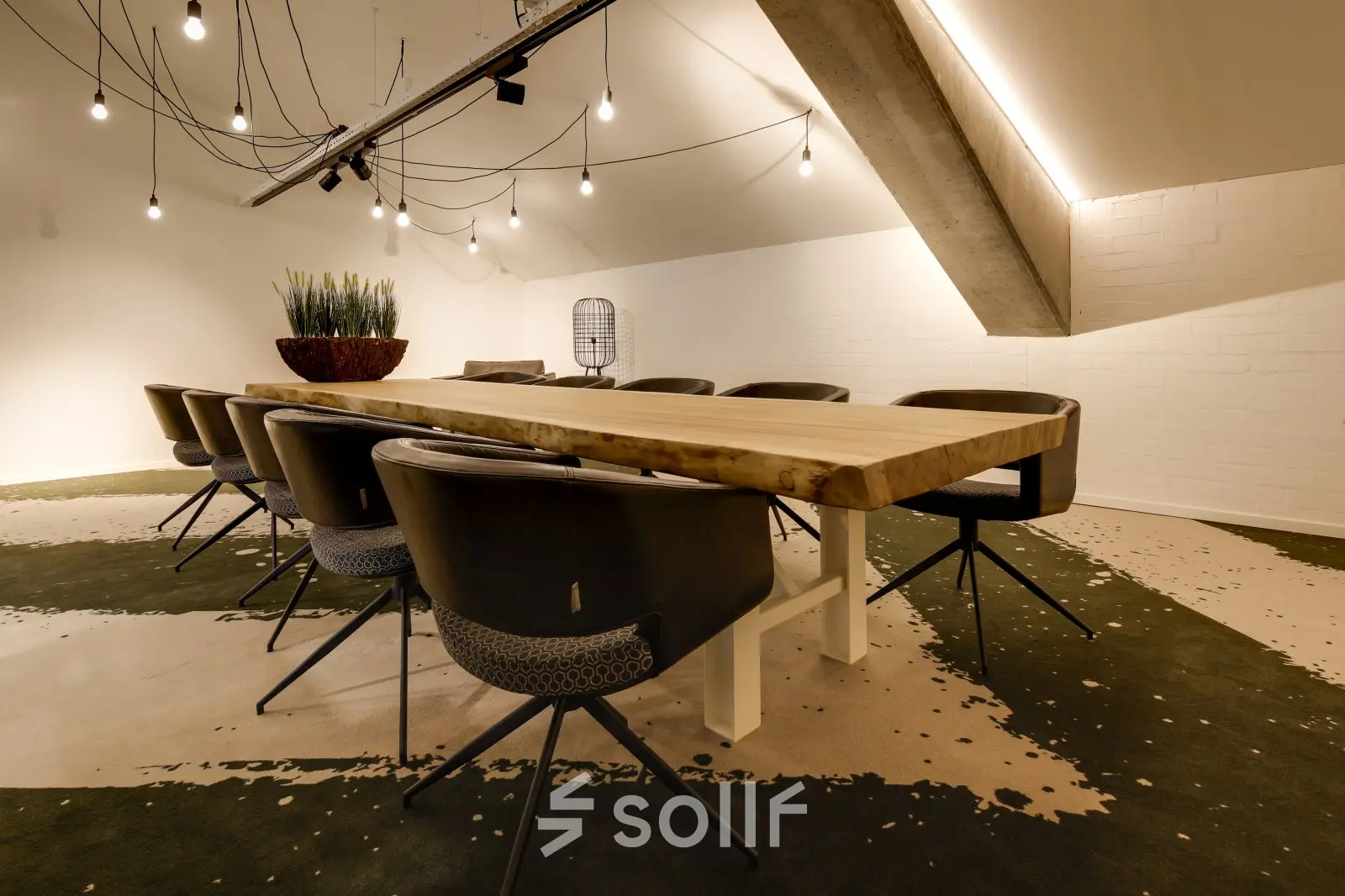 Moderne vergaderruimte in Eindhoven Strijp-S met grote houten tafel, comfortabele stoelen en sfeerverlichting, ideaal voor kantoorruimte huren.
