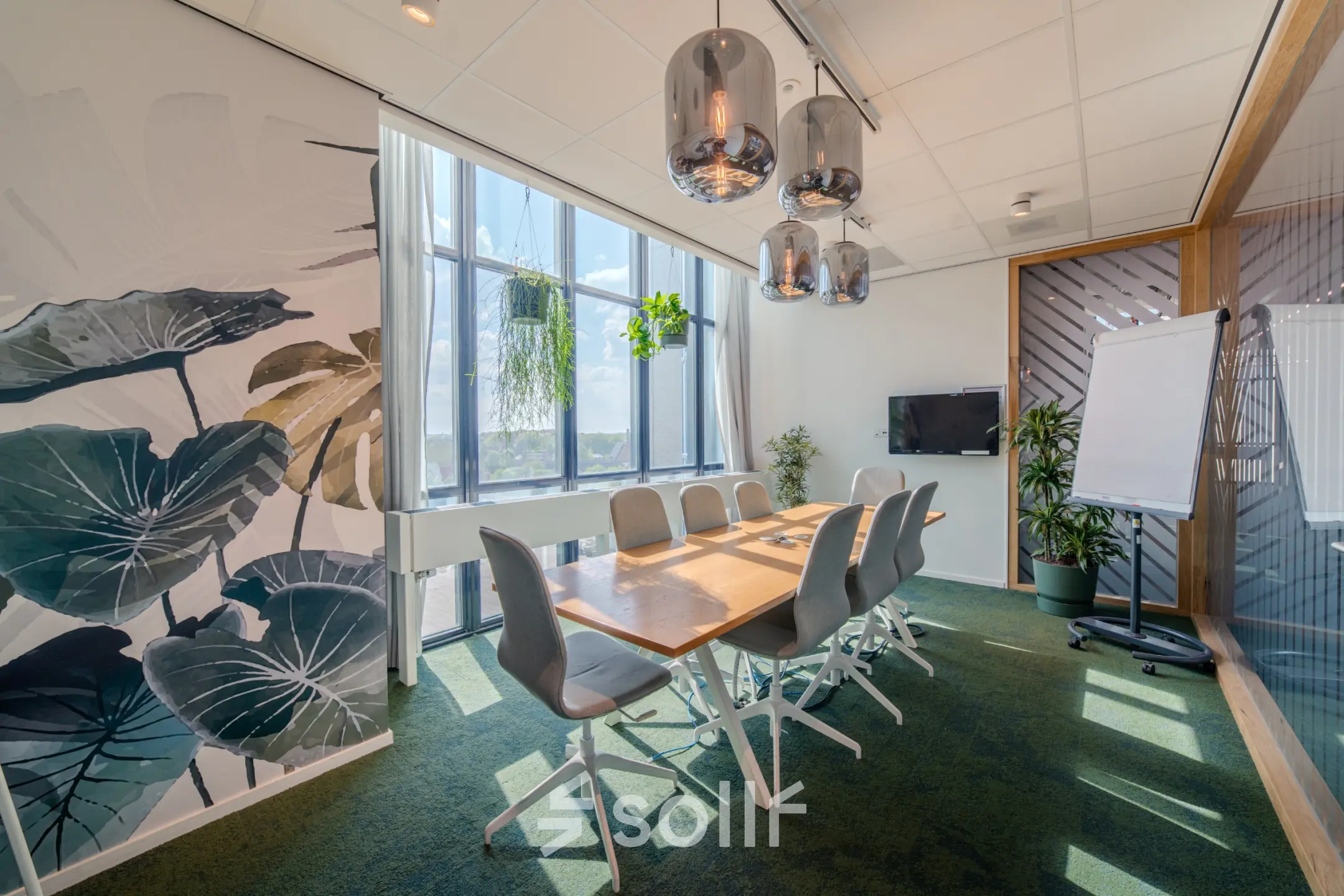 Moderne vergaderruimte met een lange houten tafel, comfortabele stoelen en veel natuurlijke lichtinval. Planten decoreren de ruimte in Eindhoven Strijp-S, Torenallee 20.