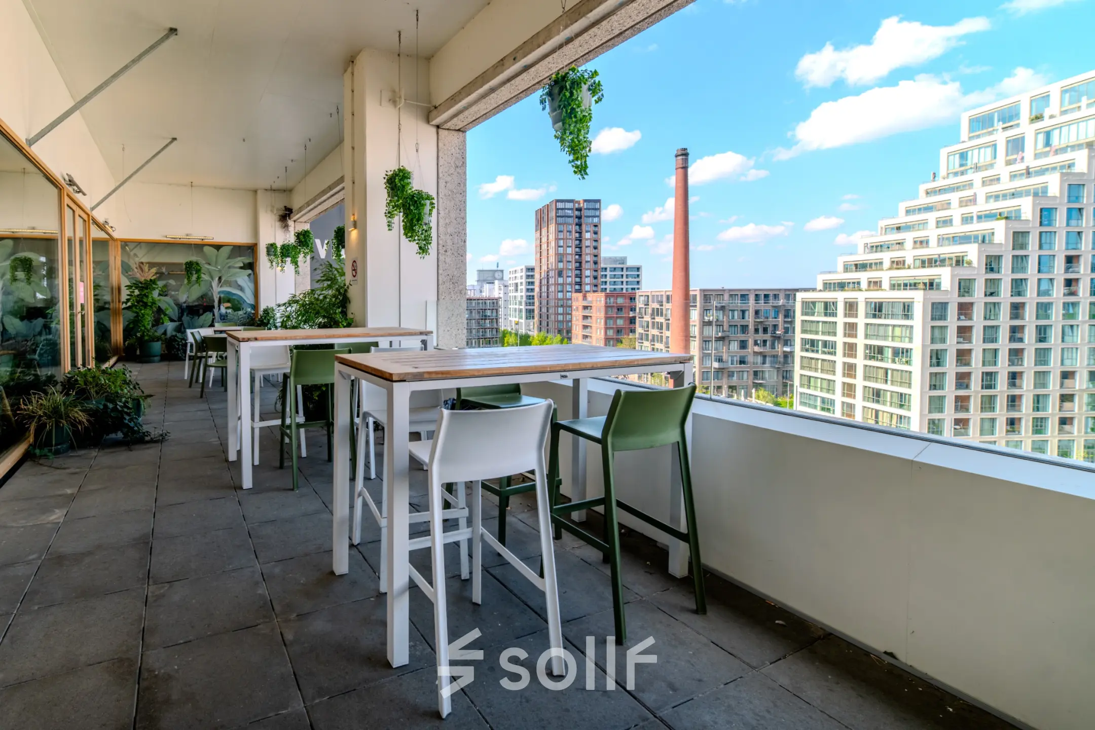 Buitenterras met moderne zitplaatsen en uitzicht op de skyline van Eindhoven Strijp-S, geschikt voor informeel werk of lunchpauzes.