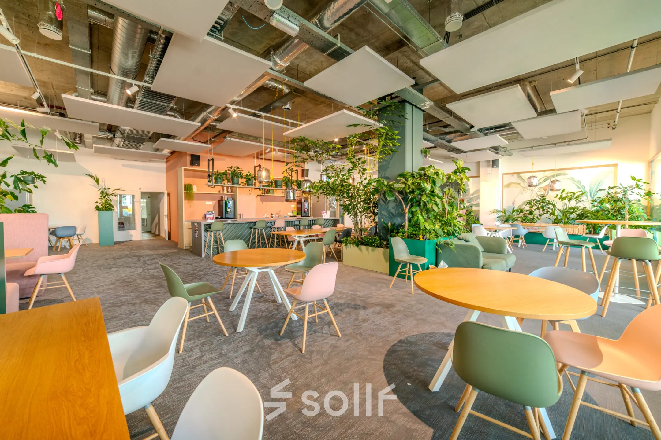 Lichte en groene werkplek in Eindhoven Strijp-S met moderne inrichting en veel planten. Ideale kantoorruimte huren met ronde tafels en comfortabele stoelen.
