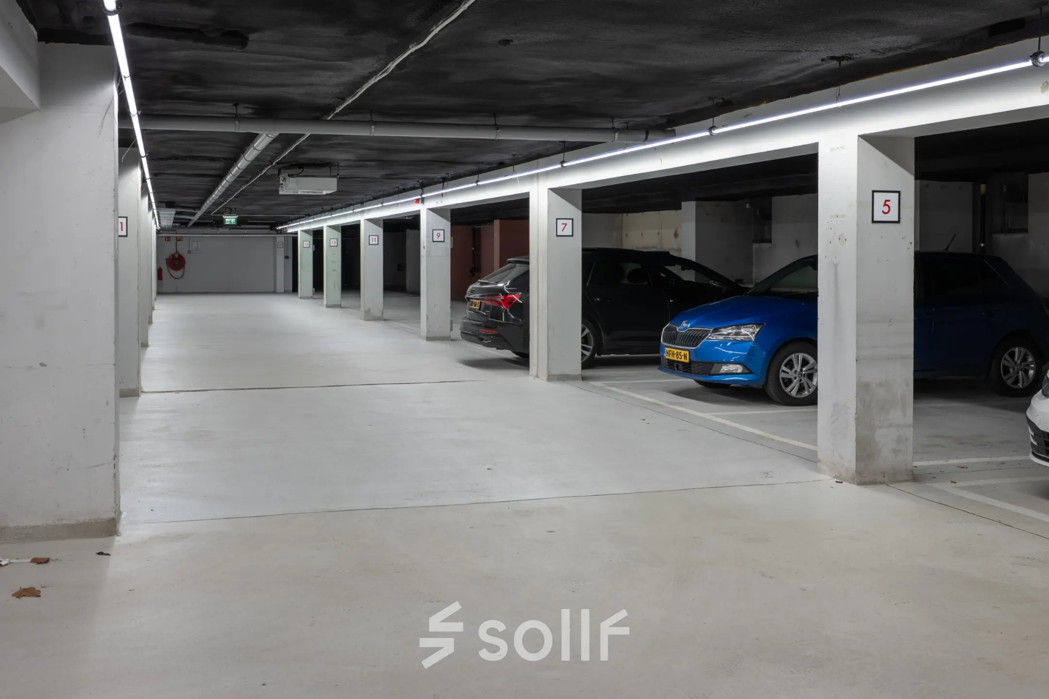 Ondergrondse parkeergarage in kantoorpand op Kuipersdijk 2-4, Enschede met betonnen muren en meerdere geparkeerde auto's.