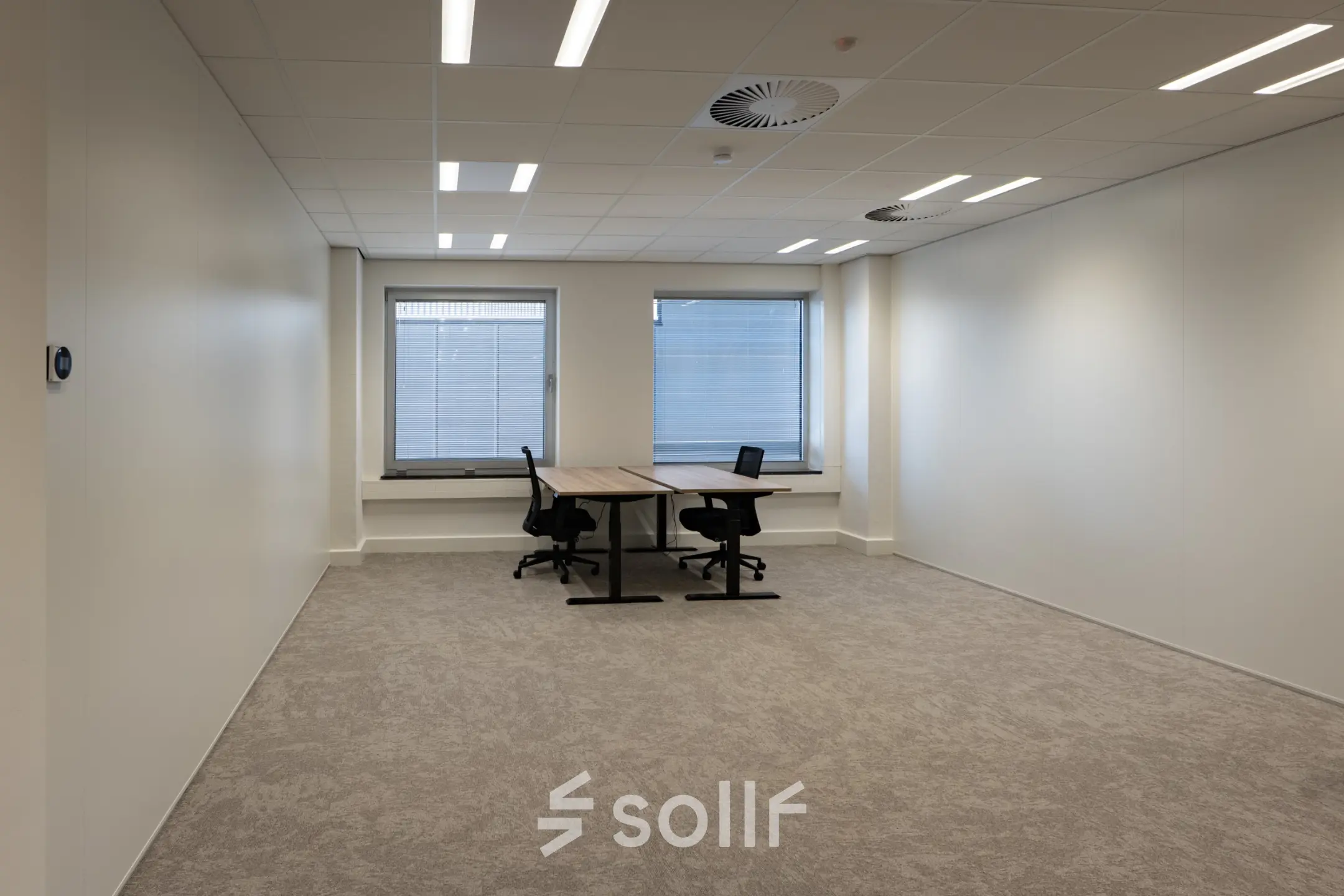 Lichte kantoorruimte met twee bureaus en stoelen, gelegen op Kuipersdijk 2-4 in Enschede, beschikbaar om te huren.