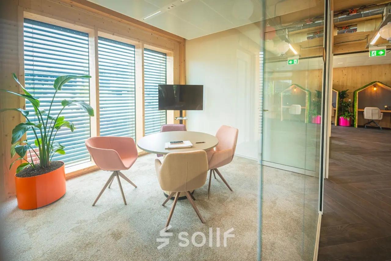 Moderne en lichte kantoorruimte in Enschede op Moutlaan 1-23 met een ronde tafel en comfortabele stoelen, ideaal voor vergaderingen. Grote ramen zorgen voor veel natuurlijk licht.