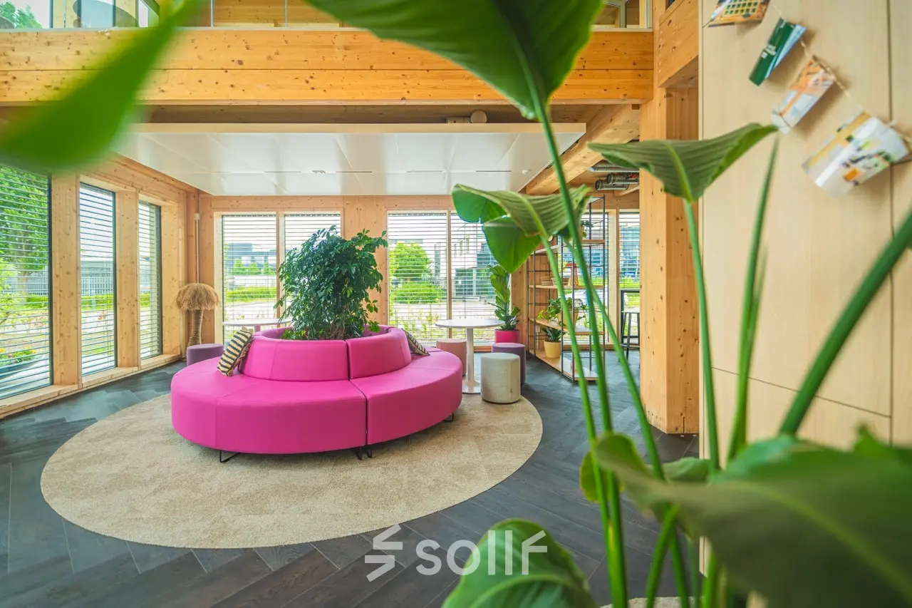 Moderne kantoorruimte huren op Moutlaan 1-23 in Enschede, met houten interieur en kleurrijke zithoek. Geschikt voor huur voor diverse zakelijke activiteiten.