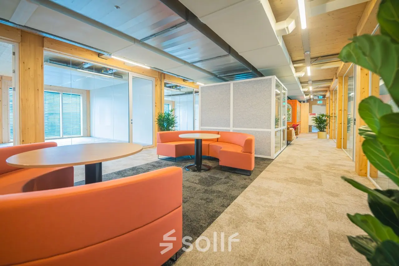 Moderne kantoorruimte in Enschede met kleurrijke zitbanken, tafels en veel lichtinval. Perfect voor ondernemers die een kantoorpand willen huren.