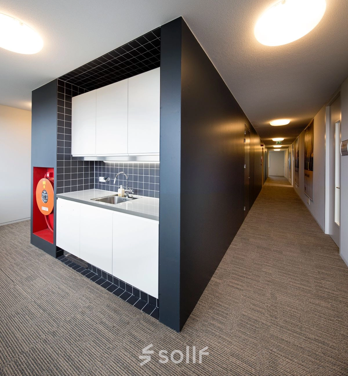 Compacte pantry in een kantoorruimte aan de Transportlaan 1-151, Geleen, met moderne zwarte tegels en witte kasten. Ideaal voor huurders die een functionele pauzeplek in een kantoorpand zoeken.
