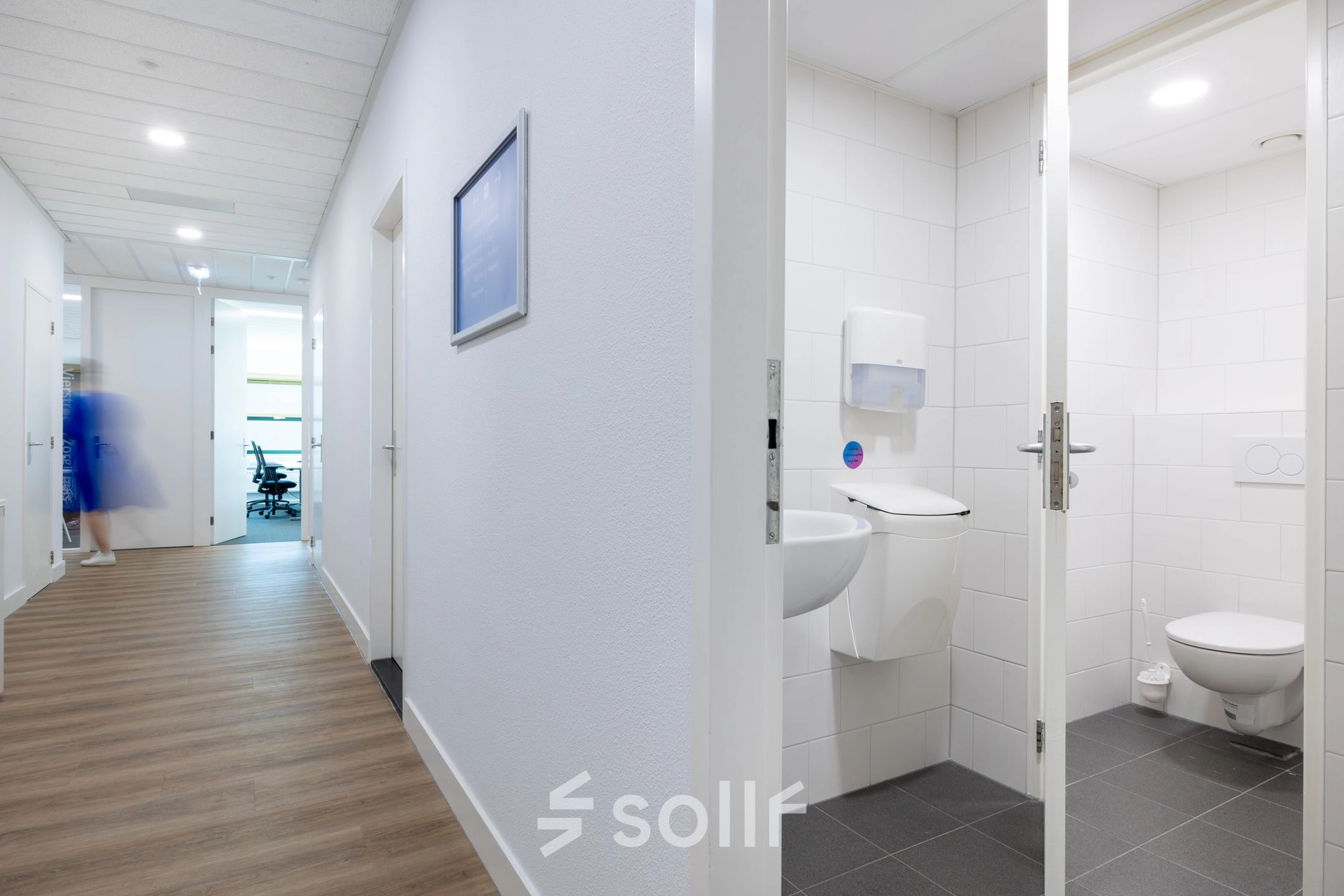 Kantoorcorridor met houten vloer, witte muren en een toilet aan de rechterkant op Groningenweg 8 8, Gouda. Perfect om een kantoorruimte te huren.