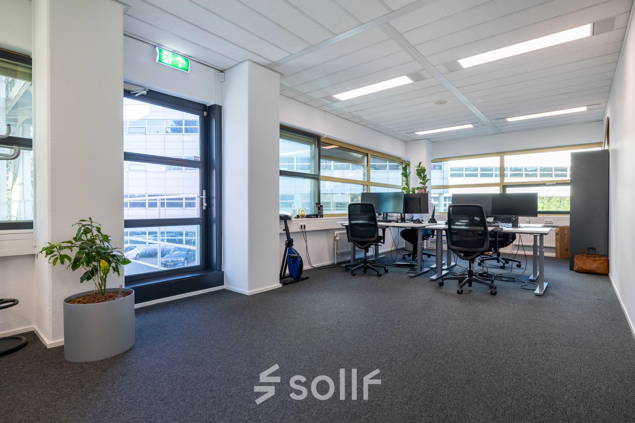 Heldere kantoorruimte met vier bureaus, stoelen en een plant in een kantoorpand op Groningenweg 8 8 in Gouda. Grote ramen zorgen voor veel licht. Ideaal voor wie kantoorruimte wil huren.