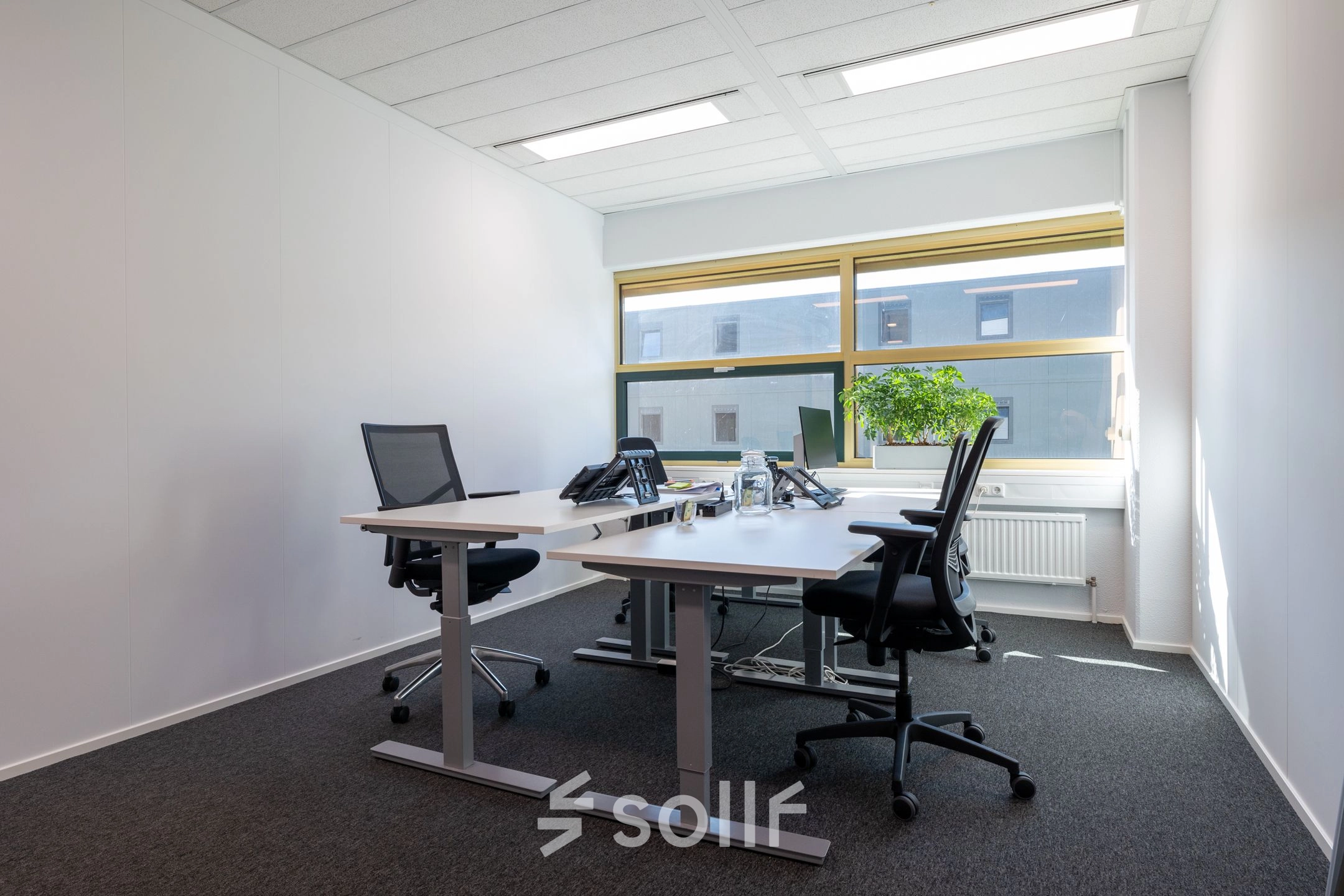 Verlichte kantoorruimte in Gouda met vier bureaustoelen en een groot raam, ideaal om te huren voor efficiënte werkplekken.
