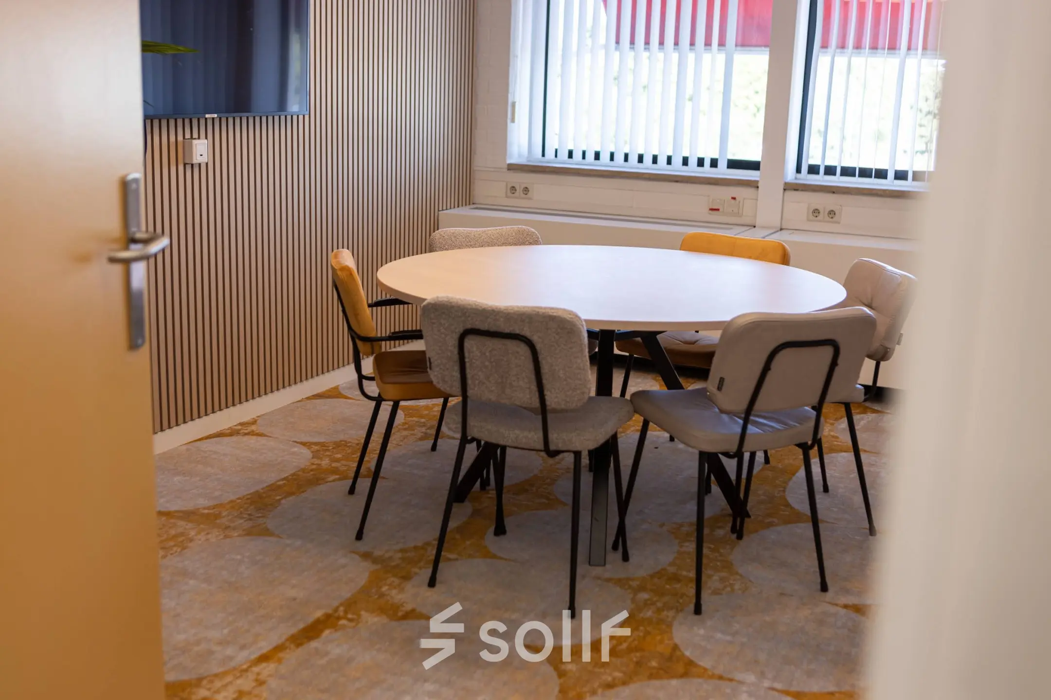 Gezellige vergaderruimte in een kantoorpand op Atoomweg 6B, Groningen met een ronde tafel omringd door diverse stoelen.