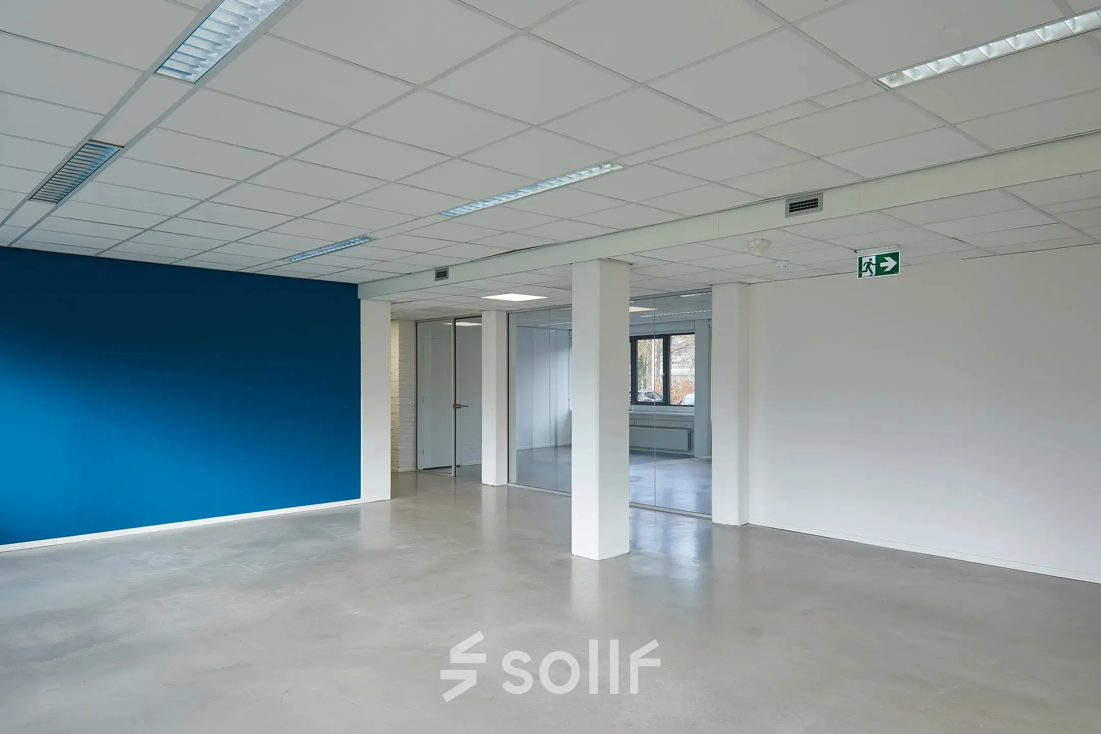 Ongebruikte kantoorruimte op Schweitzerlaan 12 in Groningen, met een opvallend blauwe muur en ramen die veel natuurlijk licht binnenlaten. Ideaal voor kantoorruimte huren.