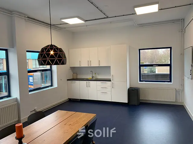Lichte kantoorruimte aan de Nijverheidsweg 50 in Haarlem Oost, ingericht met een vergadertafel en een keukenblok, ideaal voor wie een praktische kantoorpand wil huren.