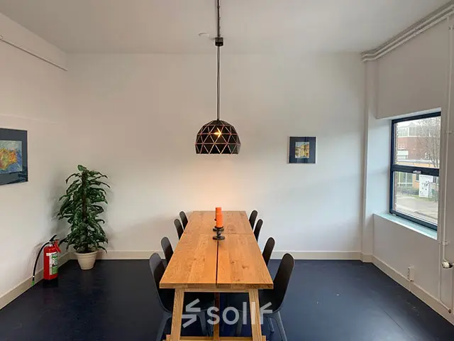 Kantoorruimte huren aan de Nijverheidsweg 50 in Haarlem Oost met een vergadertafel, stoelen en een moderne lamp. Het biedt een lichte en functionele ruimte.