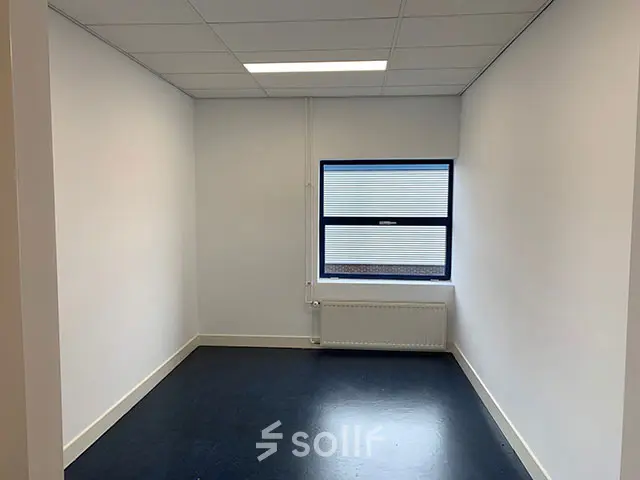 Lege kantoorruimte met een raam, witte muren en donkere vloer op Nijverheidsweg 50, ideaal voor kantoorruimte huren in Haarlem Oost.