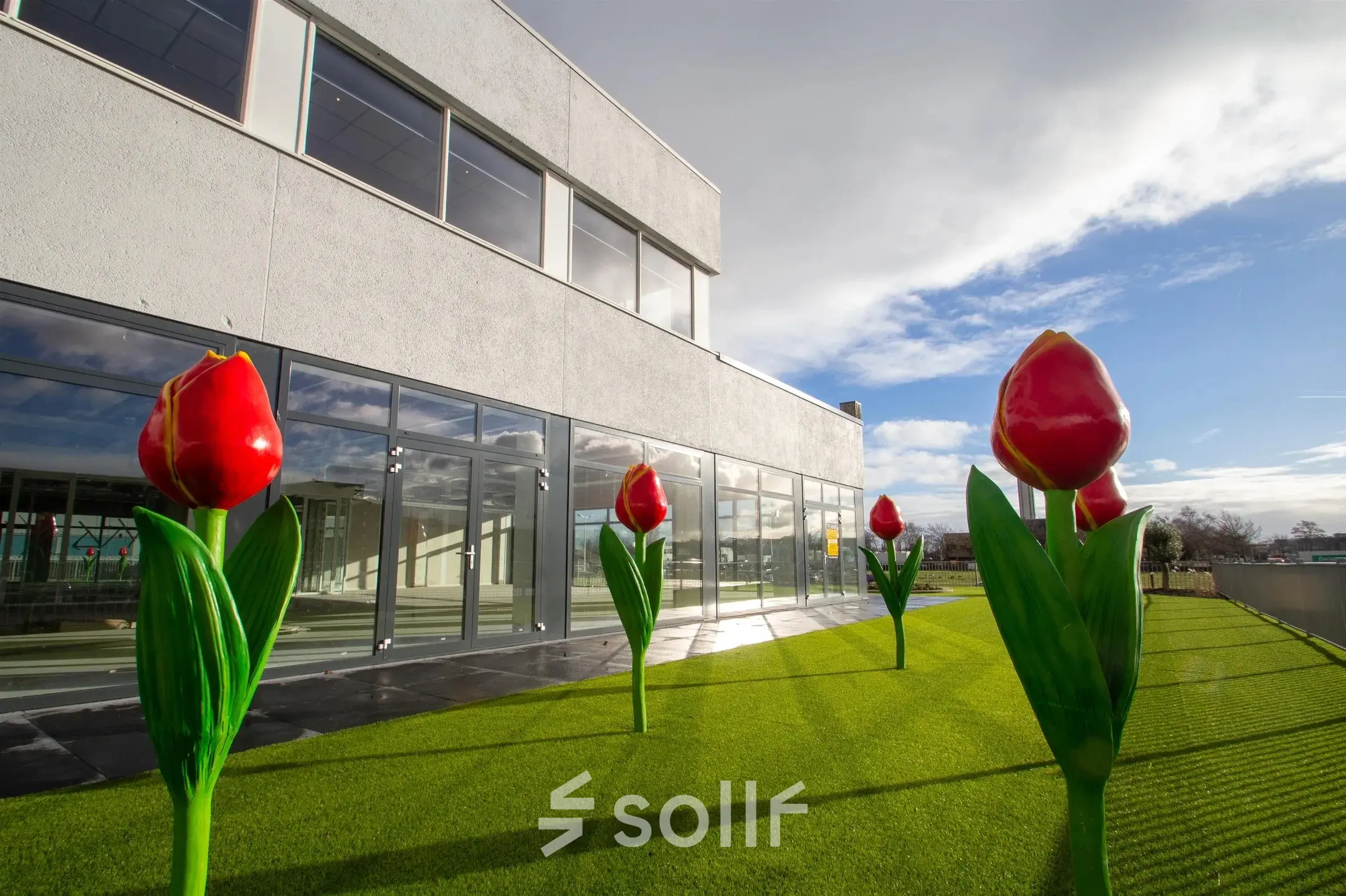 Uitzicht op de buitenzijde van het kantoorpand aan de A. Hofmanweg 5A in Haarlem Waarderpolder met opvallende tulpenkunst op het gazon.