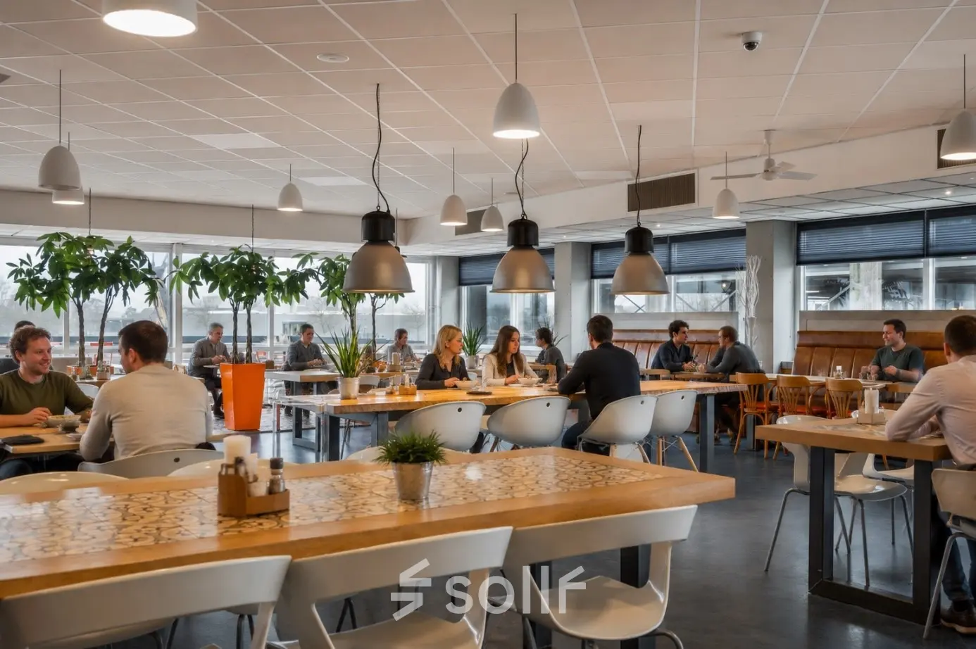 Kantoorruimte huren in een licht en gemeubileerd kantoorpand op A. Hofmanweg 5A, Haarlem Waarderpolder. Personen vergaderen en werken aan grote tafels in een open werkruimte.