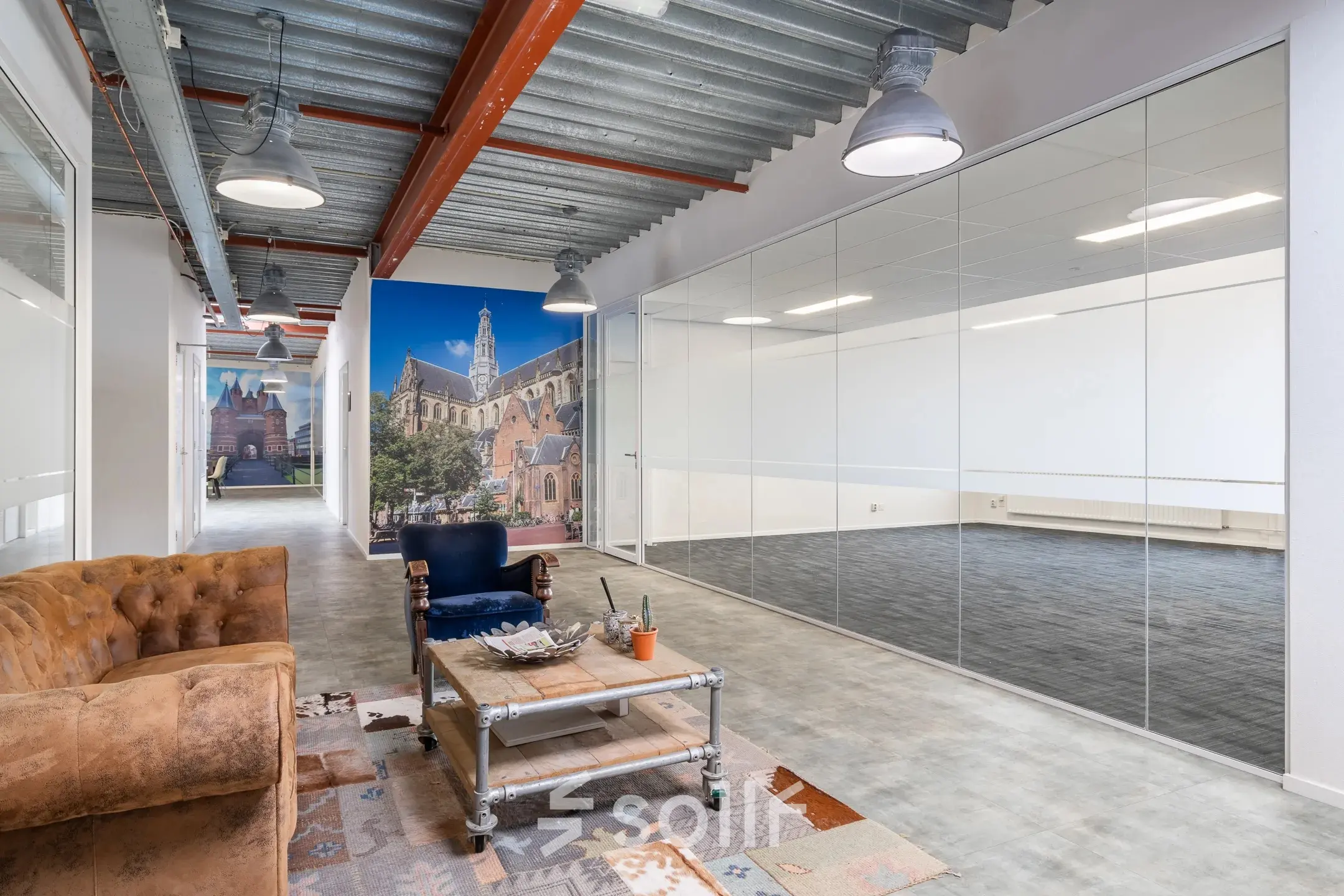 Industrieel kantoorpand te huur in Haarlem Waarderpolder aan de Bingerweg 18A - 18R met glazen wanden en een zithoek met banken en tapijt voor moderne werkruimte.