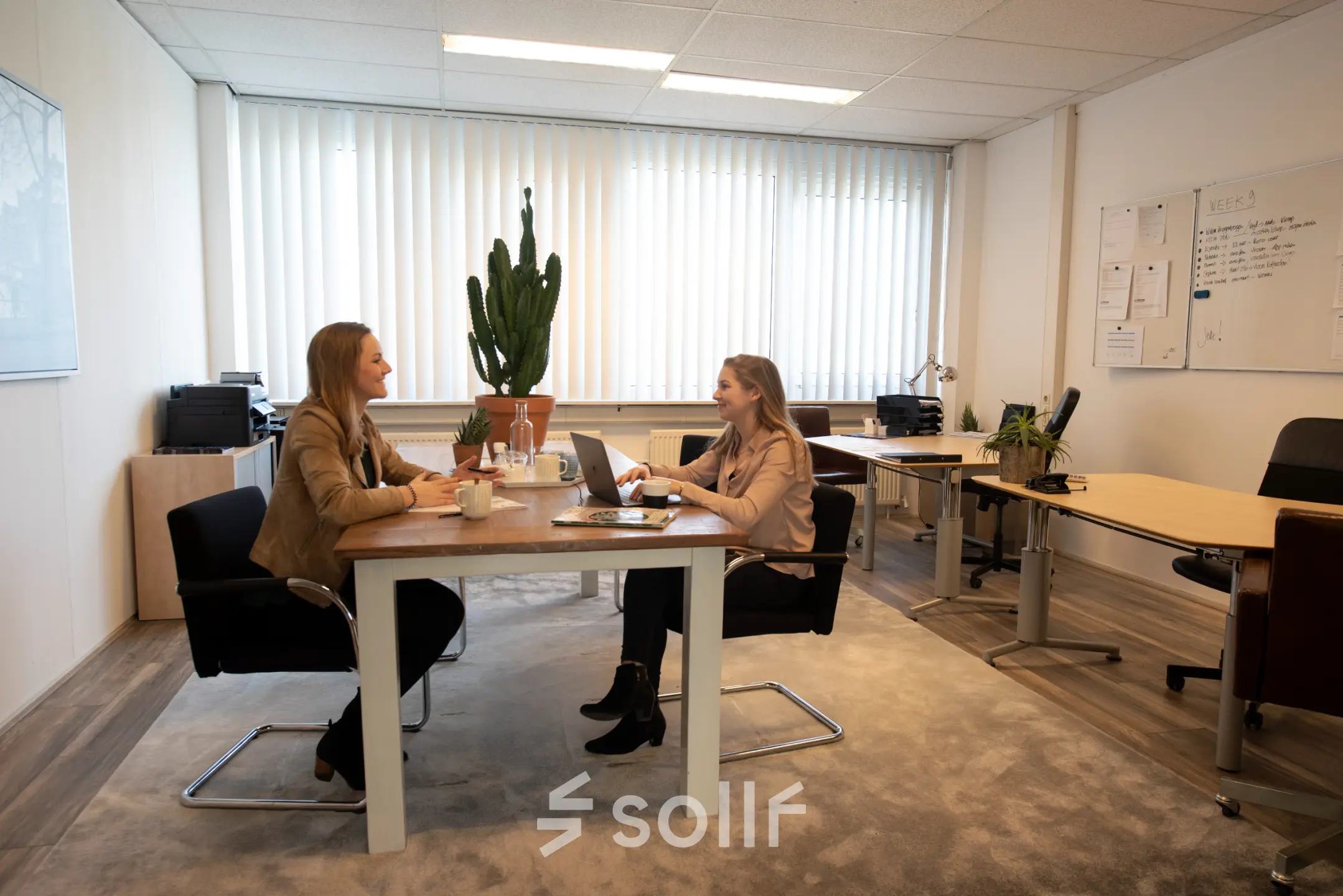 Kantoorruimte te huur op Waarderweg 19 in Haarlem Waarderpolder, met twee mensen die aan een bureau werken in een gemeubileerd kantoor met planten en kantoorpand inrichting.