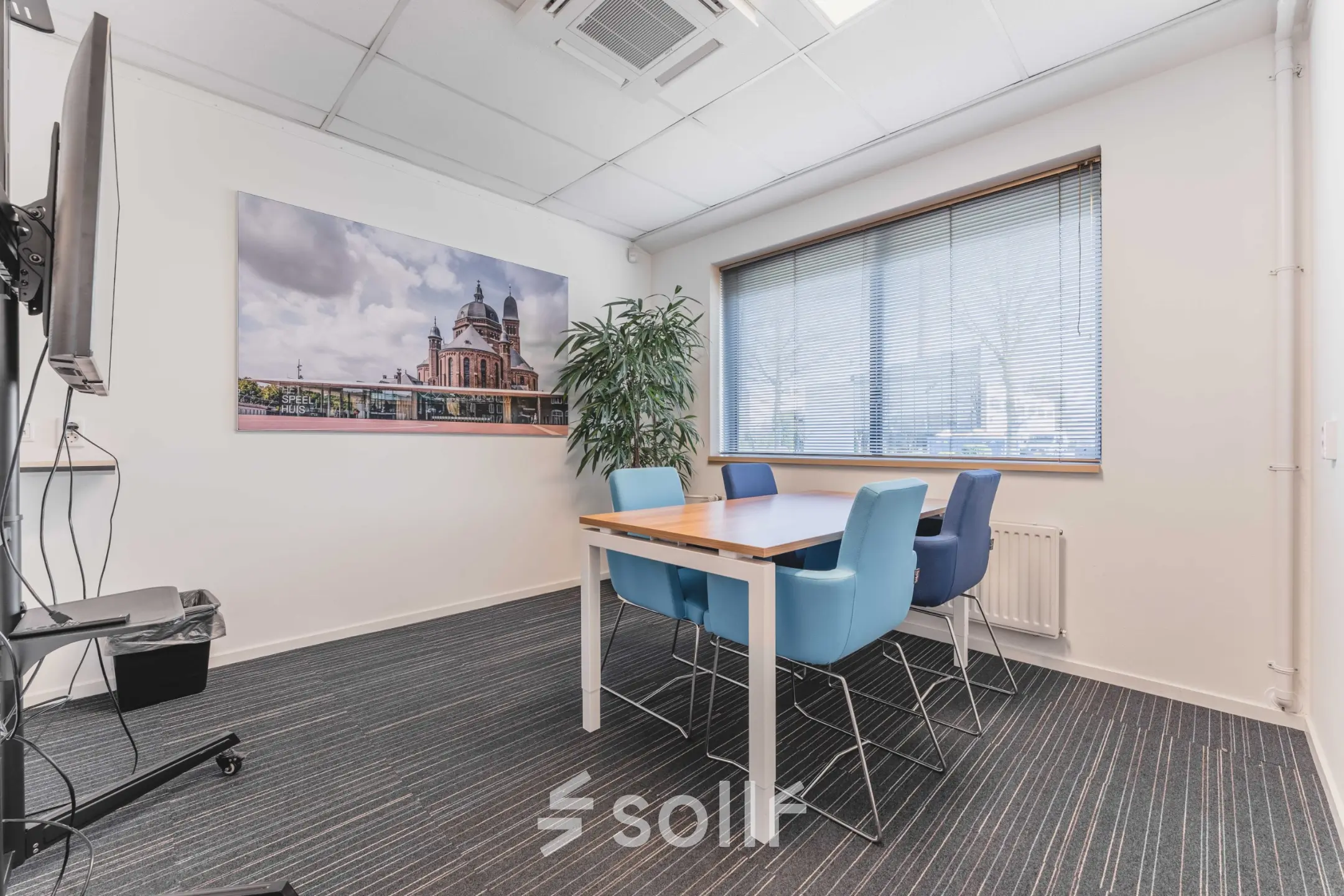 Stijlvolle vergaderruimte in kantoorpand Steenovenweg 5, Helmond. De ruimte is voorzien van moderne stoelen rondom een houten tafel, met uitzicht door een groot raam.