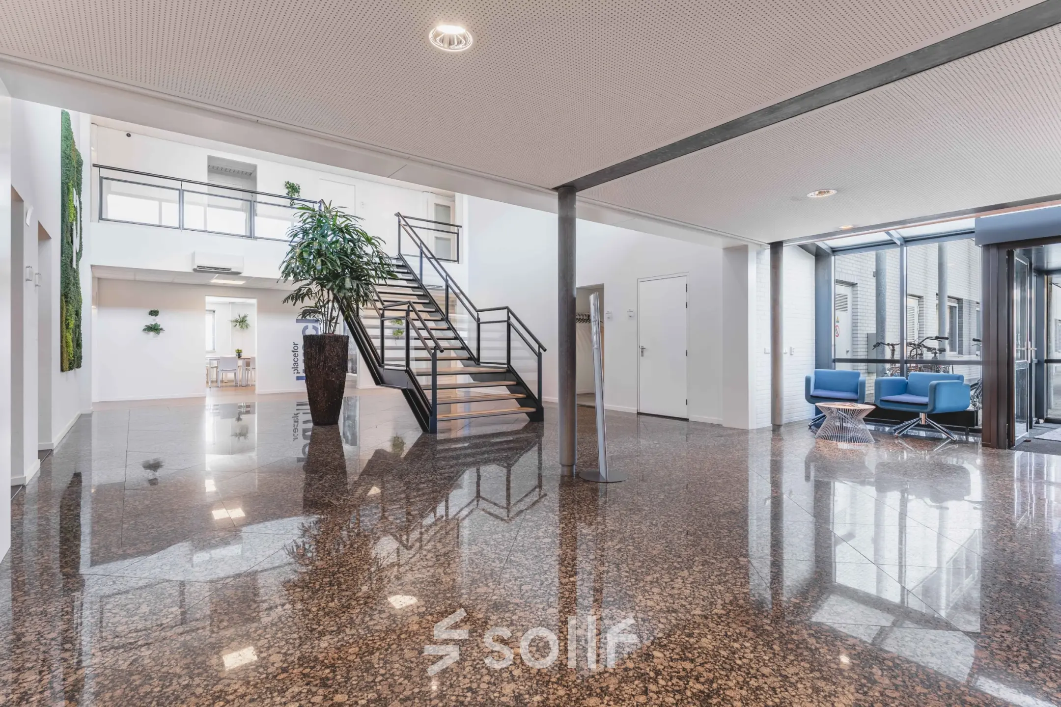 Ruime entree in het kantoorpand aan de Steenovenweg 5 in Helmond, met glazen gevels en een moderne trap. Ideaal voor wie kantoorruimte wil huren in een professionele omgeving.