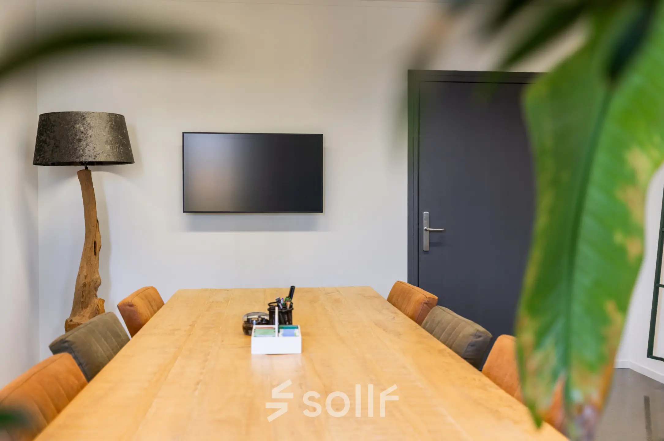 Stijlvolle kantoorruimte huren op Demmersweg 3 in Hengelo met een houten tafel, comfortabele stoelen en een moderne lamp.