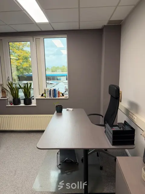 Kantoorruimte huren op Hamerstraat 10, Hengelo. Een strak ingerichte ruimte met bureaus, een comfortabele stoel en uitzicht op de buitenomgeving.
