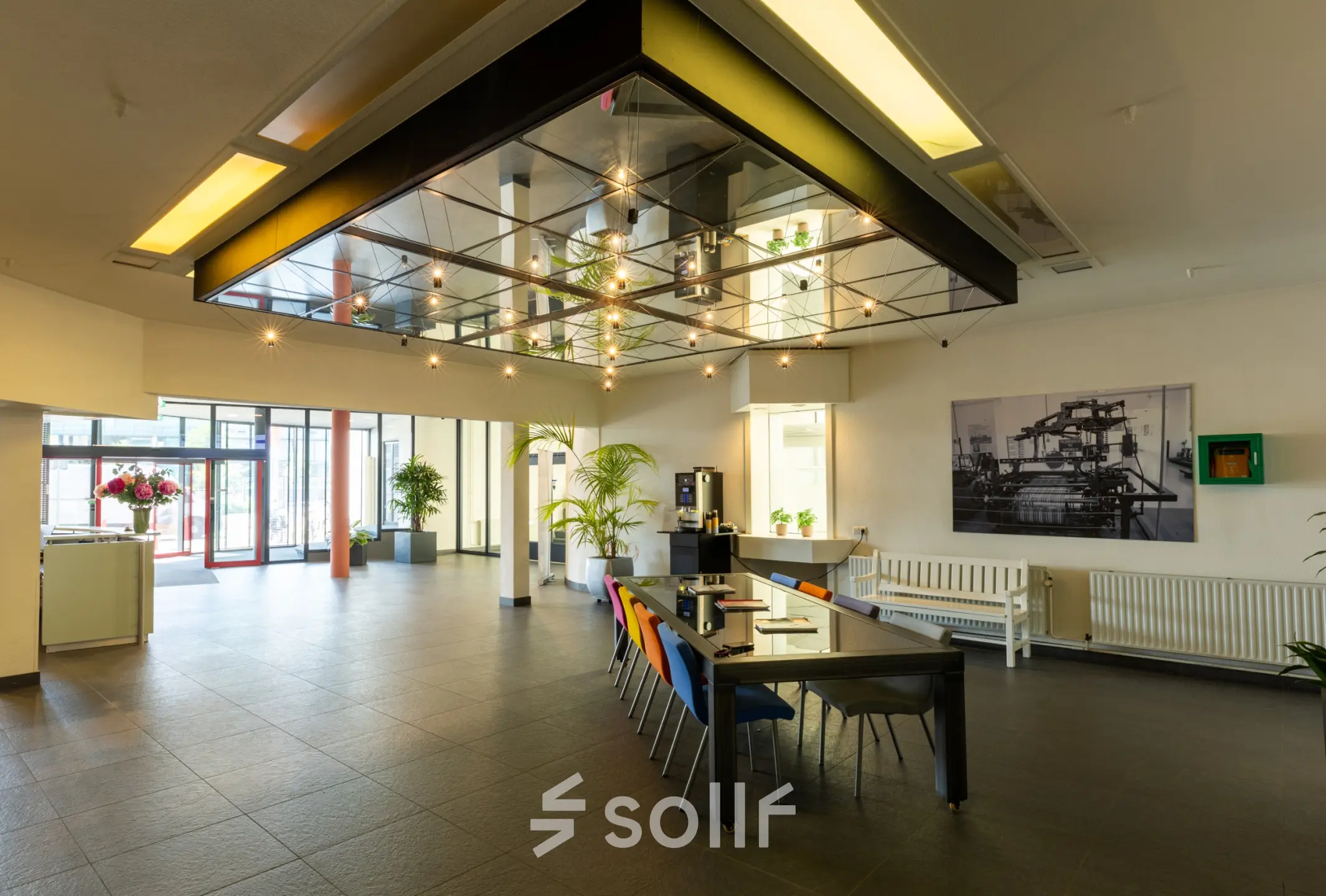 Kantoorruimte te huur op Lansinkesweg 4 in Hengelo met stijlvolle inrichting, moderne verlichting en kleurrijke stoelen rond een lange tafel.