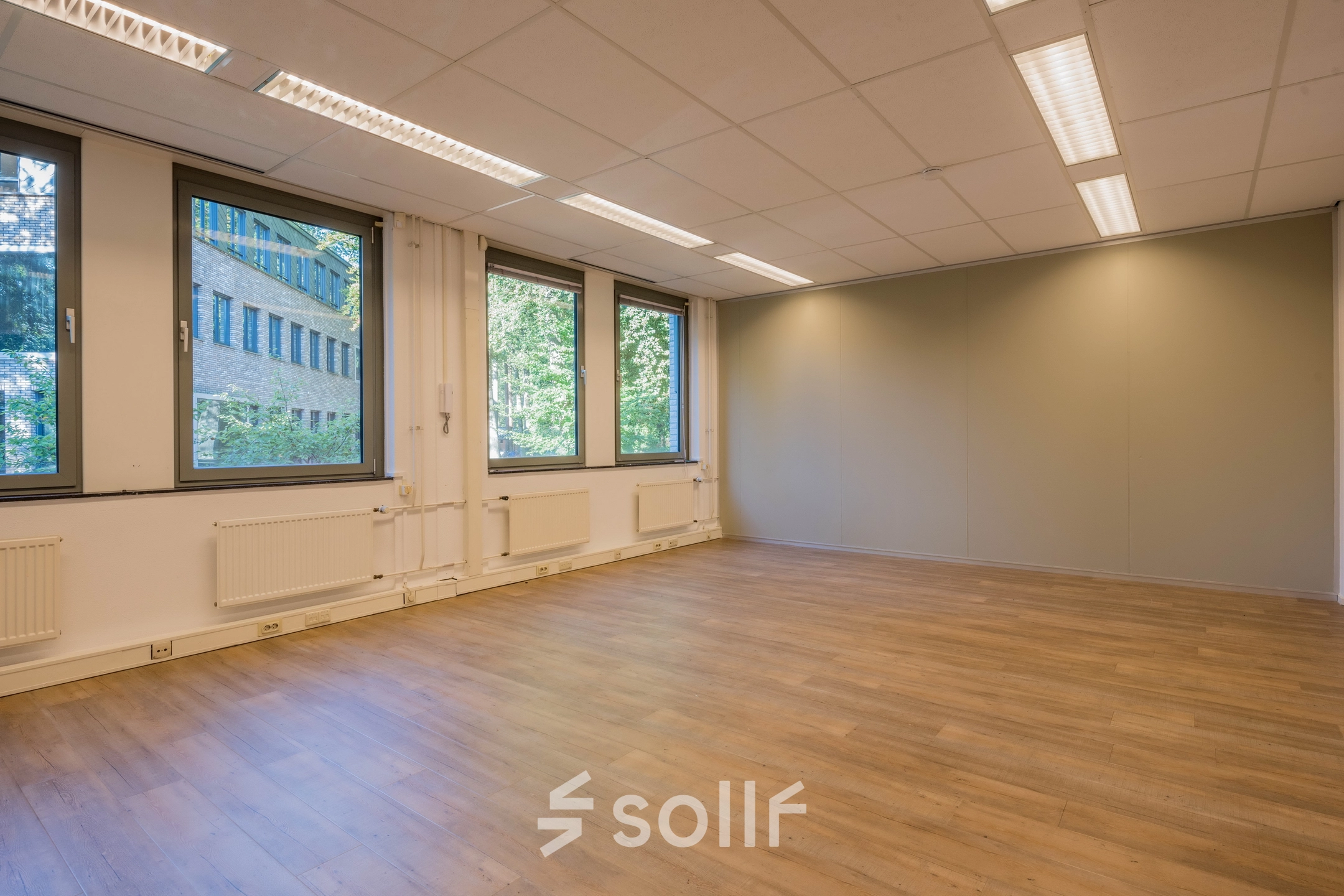 Lichte en ruime kantoorruimte te huur op Mozartlaan 25, Hilversum, met grote ramen en houten vloer, ideaal voor een open werkruimte.