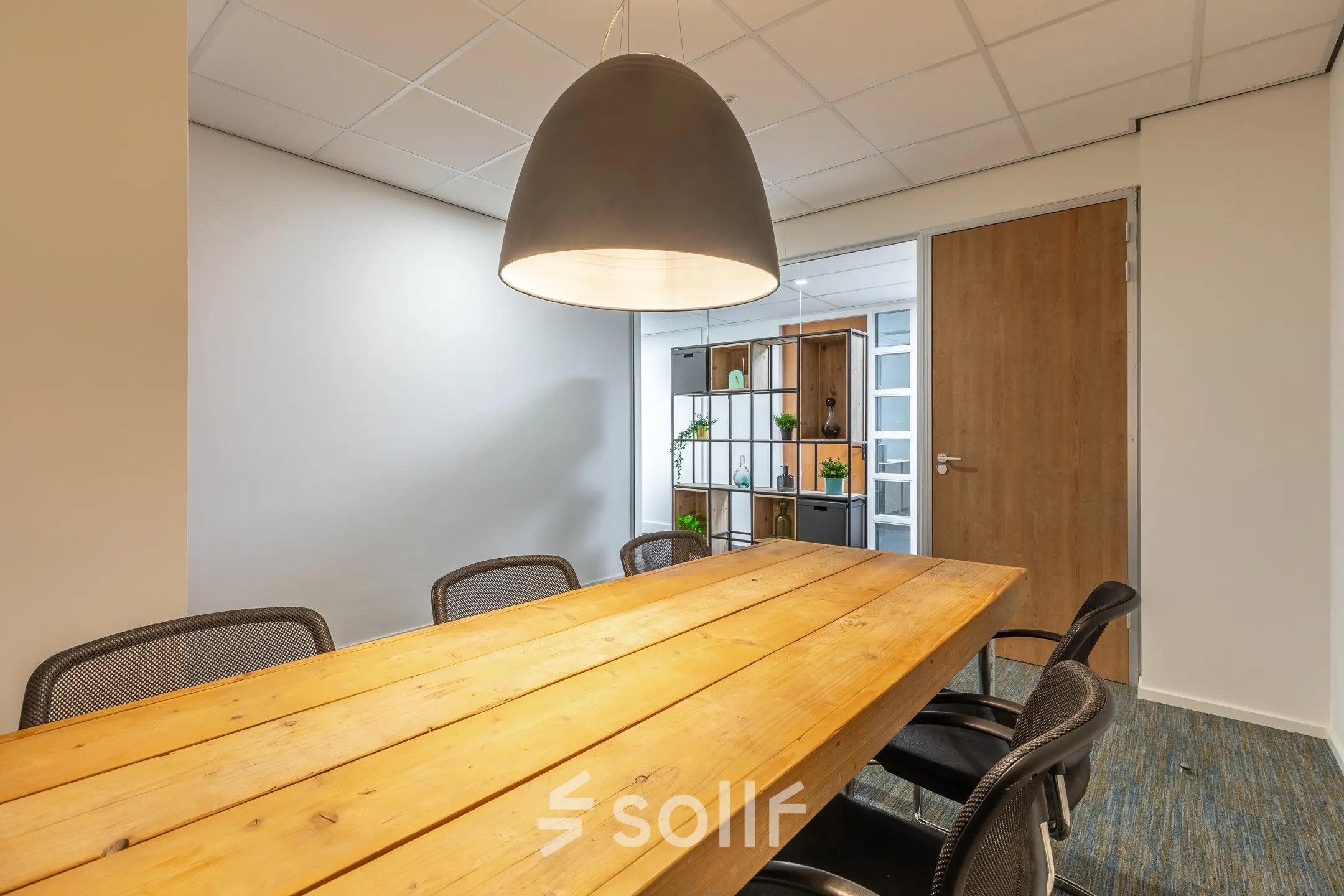 Stijlvolle kantoorruimte met houten tafel en moderne stoelen op Mozartlaan 27, Hilversum. Zoek je kantoorruimte te huur? Hier kan het. Veelzijdig en functioneel, perfect voor je zakelijke ontmoetingen.