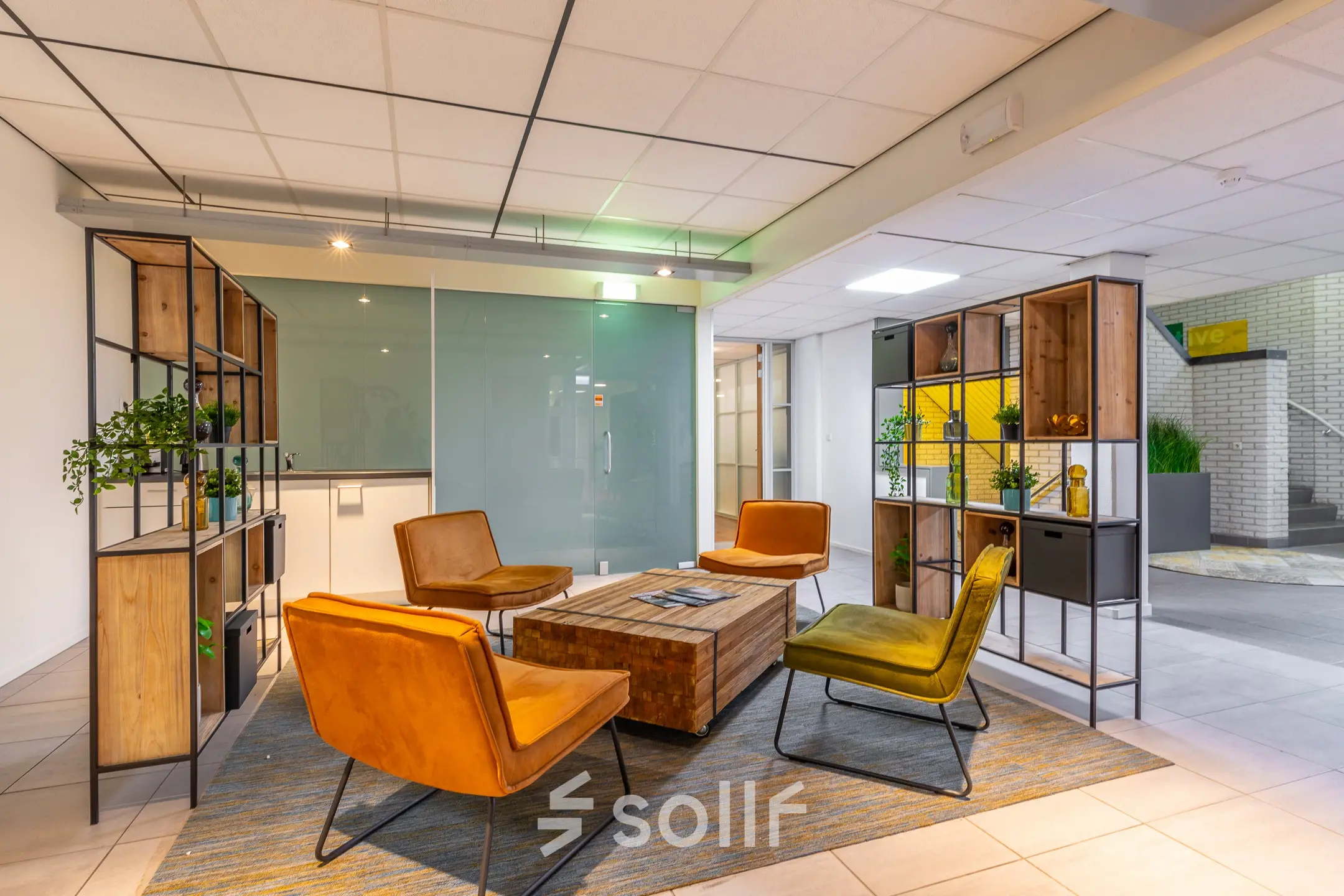 Moderne kantoorruimte met kleurrijke fauteuils en houten tafels op Mozartlaan 27, Hilversum. De ruimte is ingericht met trendy meubels en planten, ideaal voor een warme en uitnodigende werkomgeving.