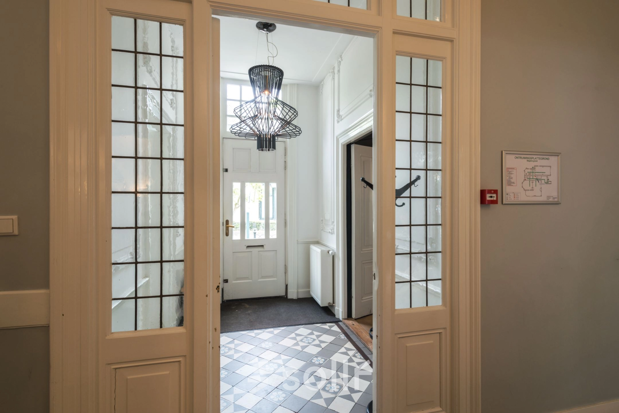 Ingang van een kantoorpand aan de Oude Enghweg 8 in Hilversum met glazen deuren en een decoratieve tegelvloer. Ideale plek om kantoorruimte te huren.