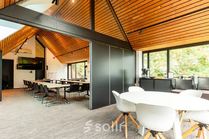 Ruime en lichte kantoorpand op Steijnlaan 16, Hilversum met moderne inrichting en houten accenten, ideaal voor kantoorruimte huren met open werkplekken en een vergadertafel bij het raam.