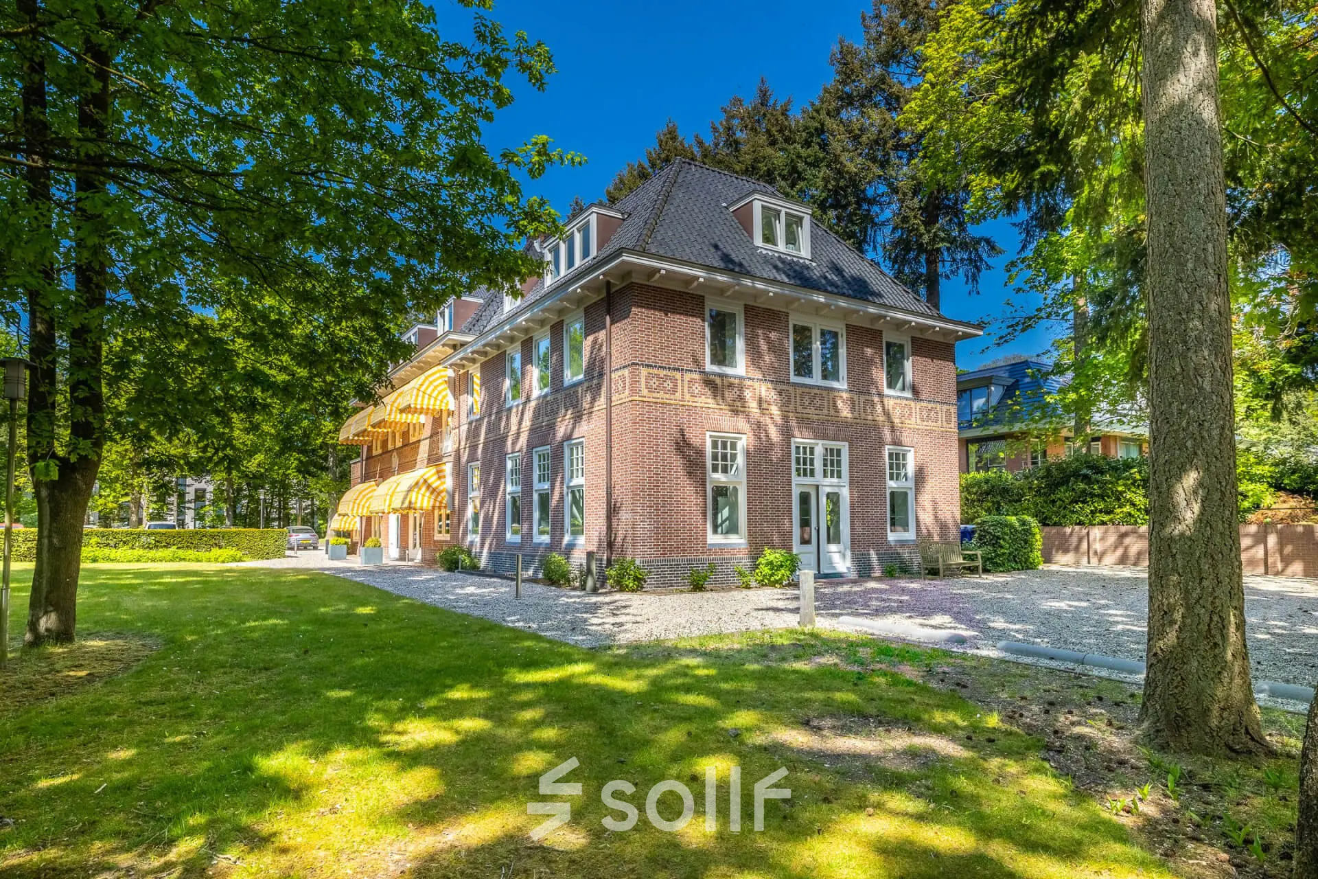Historisch kantoorpand op Utrechtseweg 47 in Hilversum omgeven door groen.