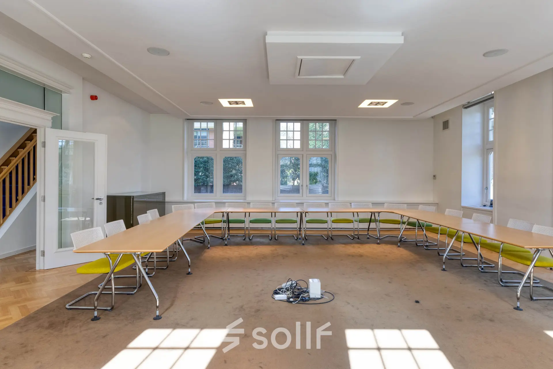 Kantoorruimte huren in Hilversum met een lichte vergaderruimte, voorzien van tafels, stoelen en een tapijtvloer. Ideaal voor zakelijke bijeenkomsten.